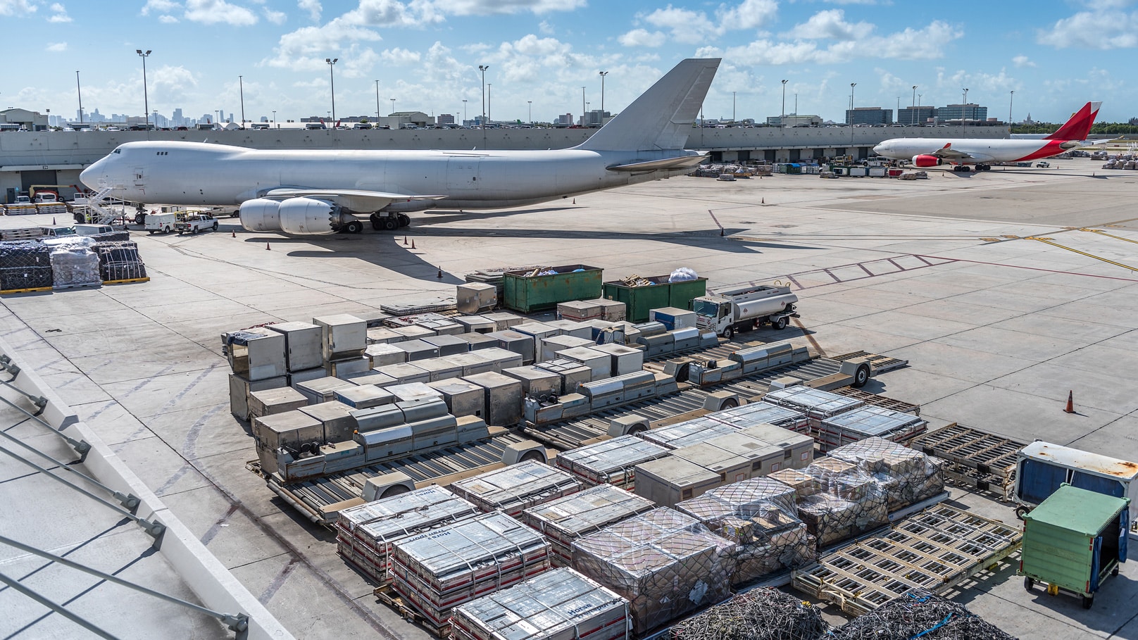 Cargo Management Systems streamline pallets on an airport tarmac with planes in the background.