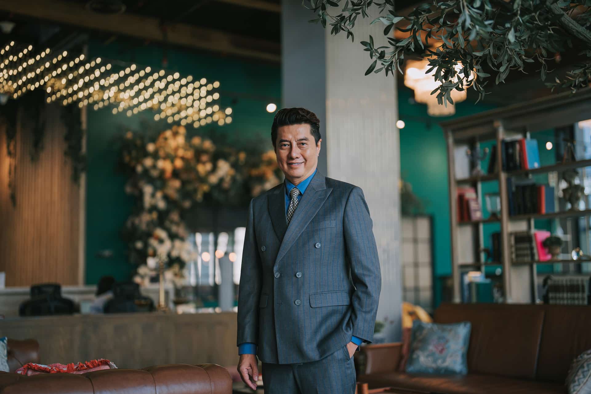 A man in a blue suit smiles, embodying Experiential Travel in a stylish, modern lounge.