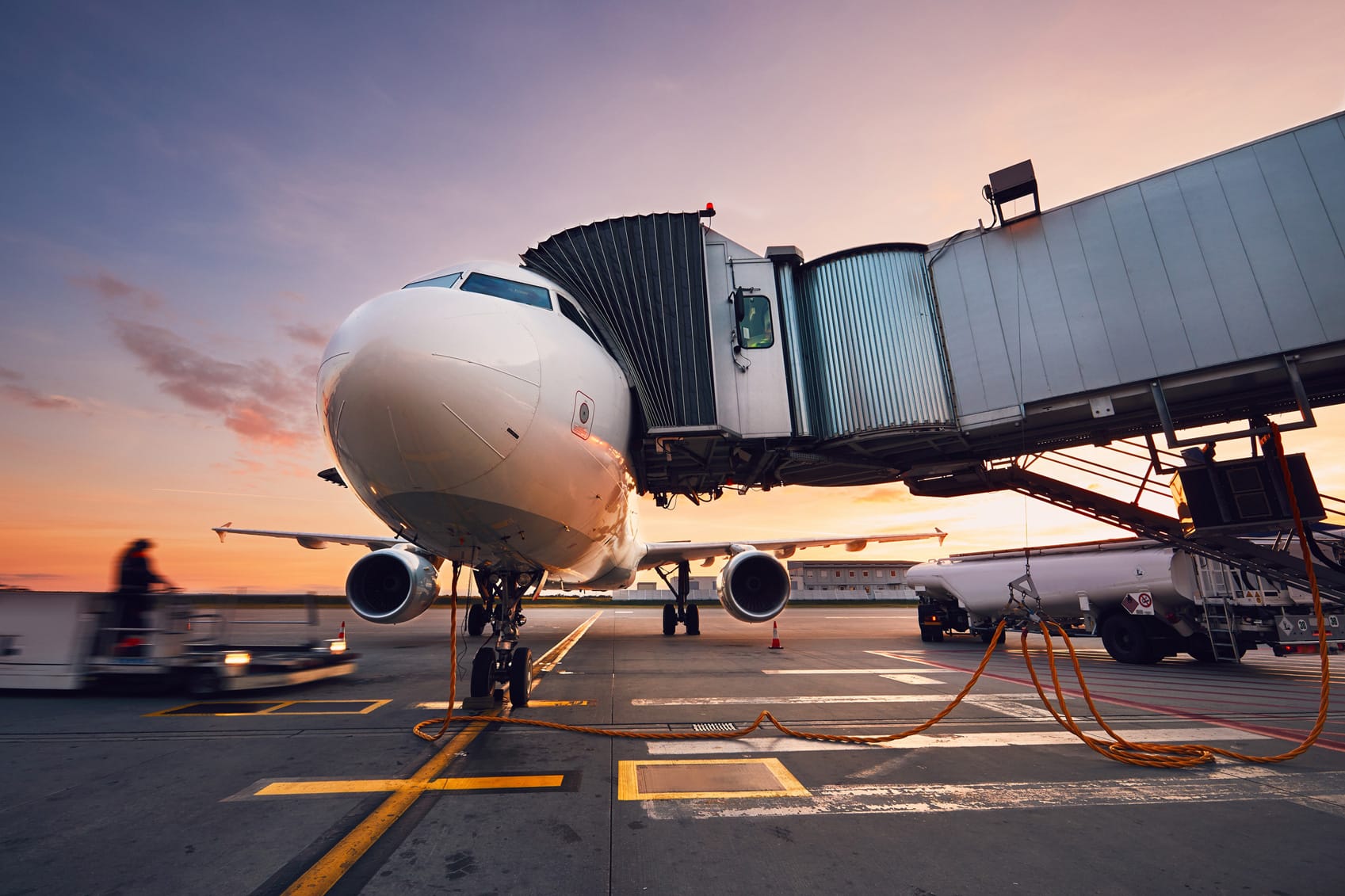 Airplane at gate during sunset, with ground operations and turnaround management underway.