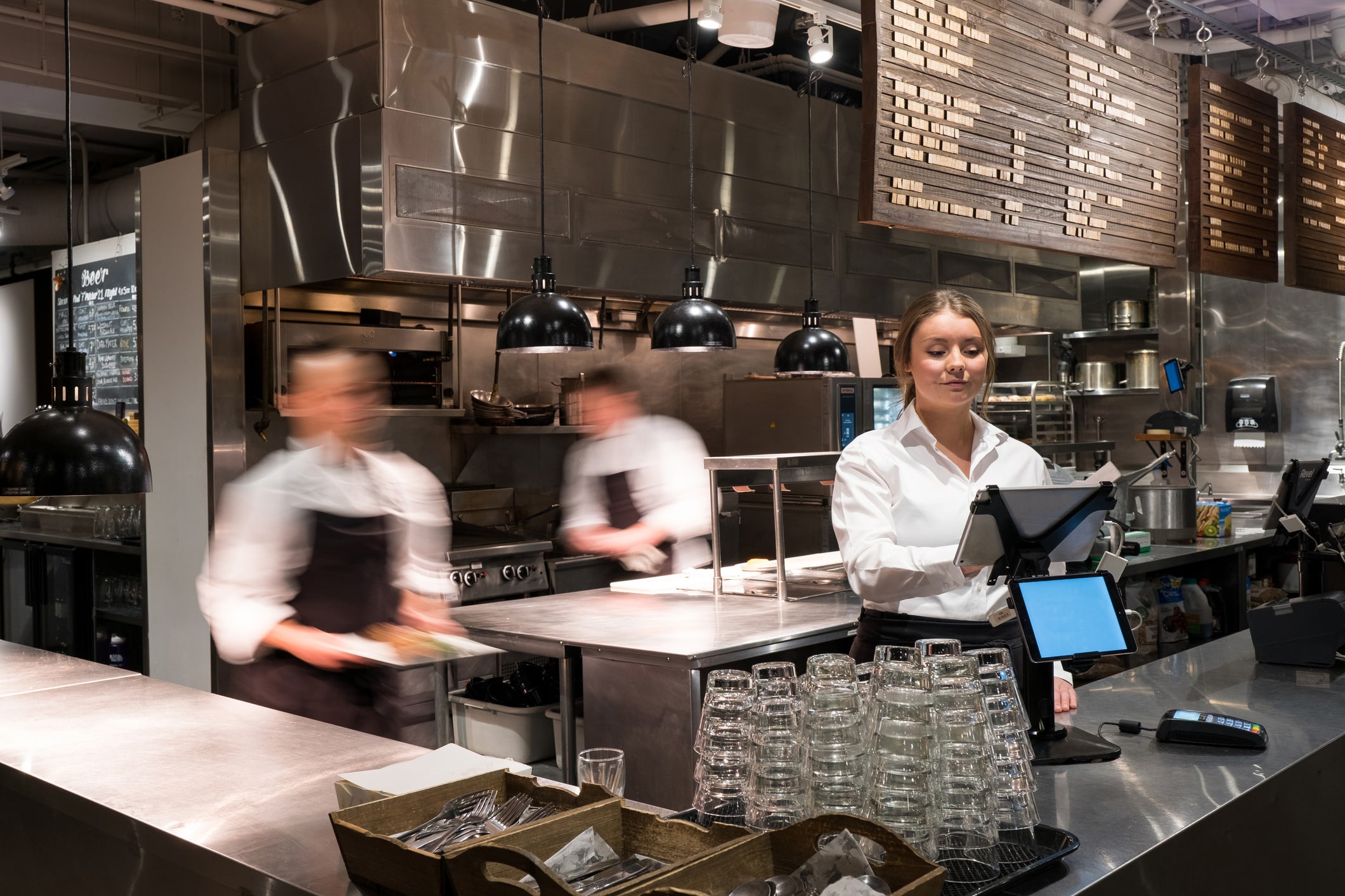 Restaurant staff embody hospitality behind the counter, at the register, others blurred in motion.