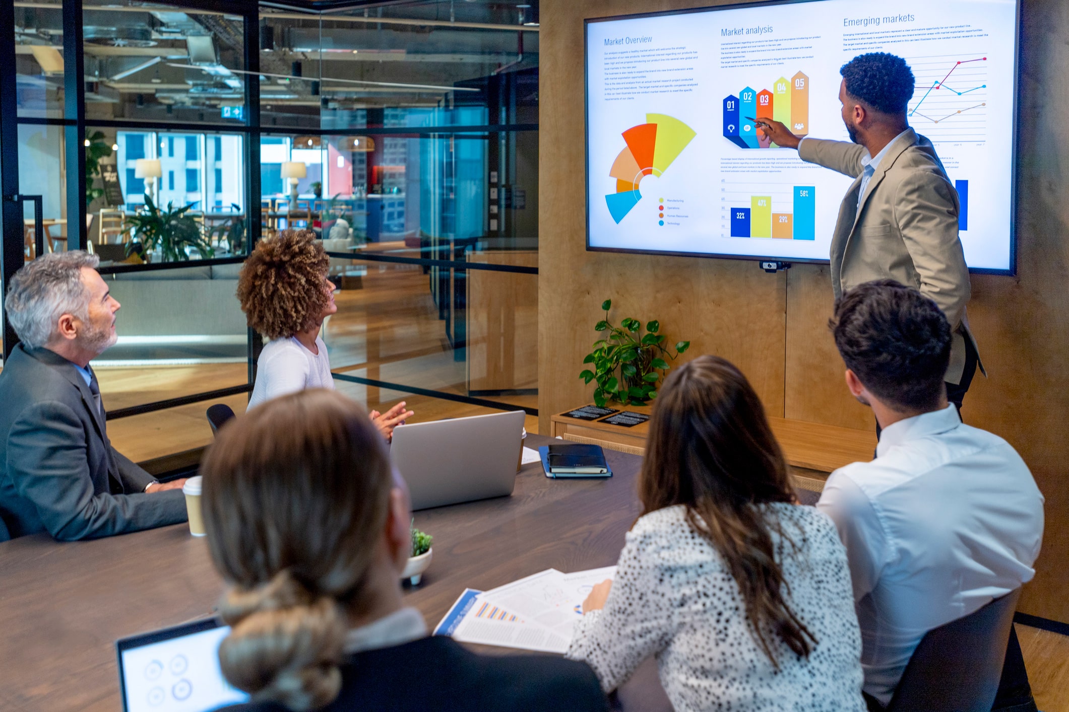 Man presenting Channel Economics charts to colleagues in a modern conference room.