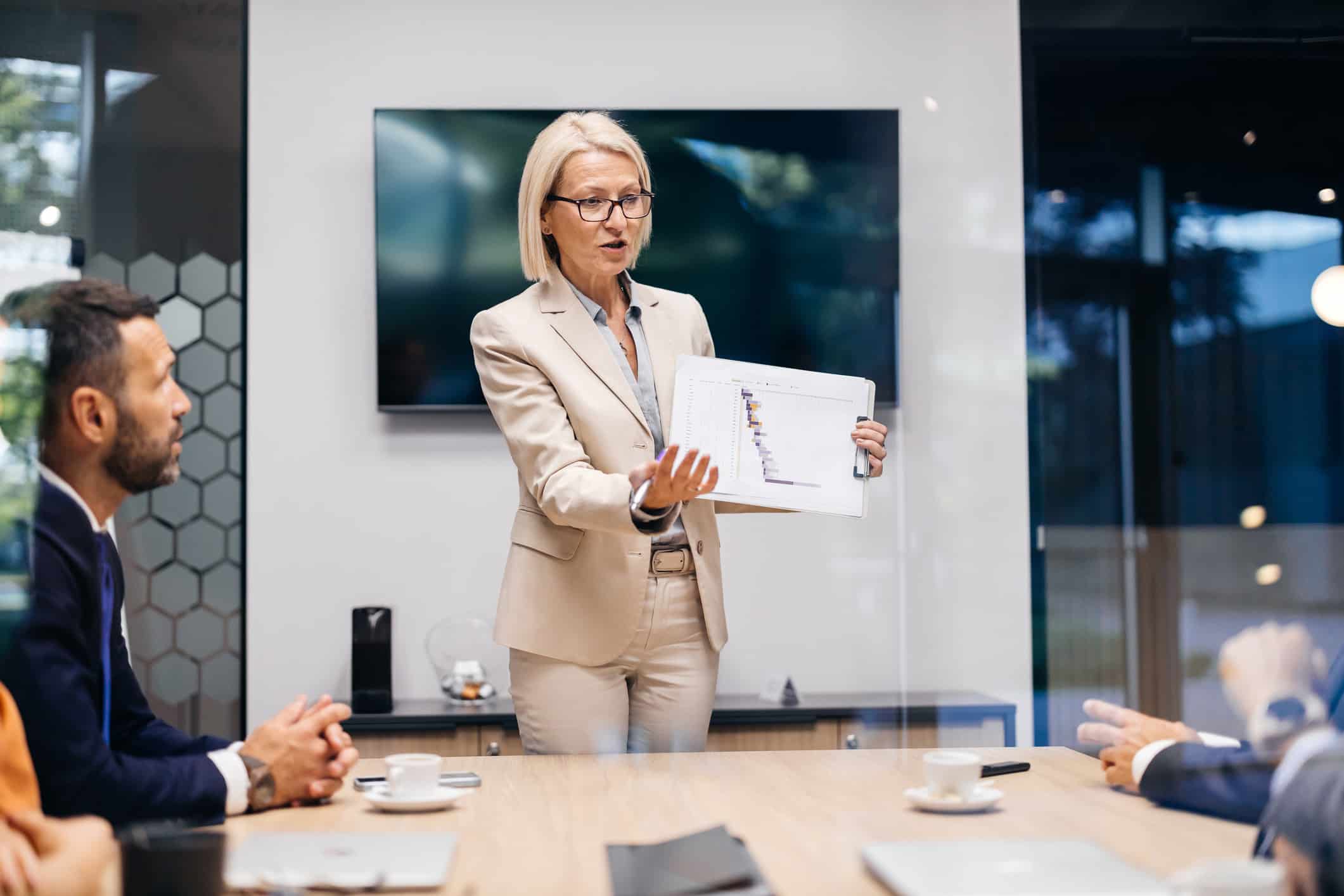 Businesswoman presenting a chart on Digital Guest Journey Mapping to colleagues in meeting room.