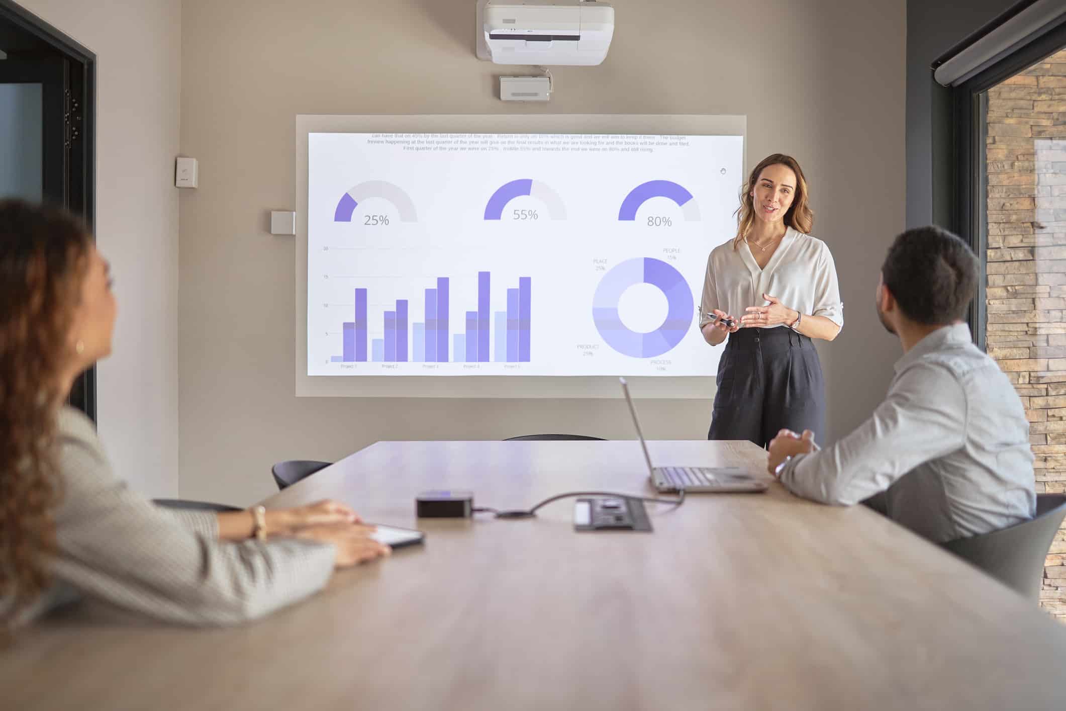 Woman presenting charts on Hospitality Finance Transformation Consulting in conference room.