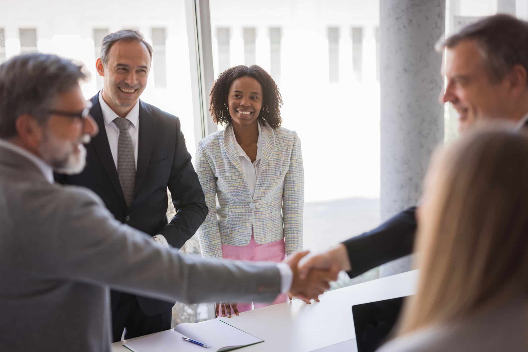 Four professionals in business attire discuss market expansion and global partnership consulting.