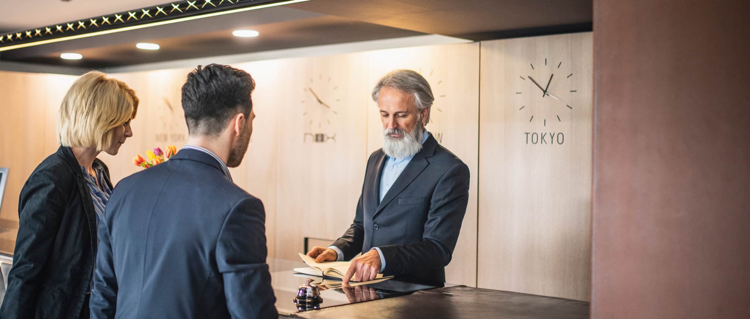 Hotel receptionist assists guests at the front desk, showcasing Hospitality Digital Transformation.