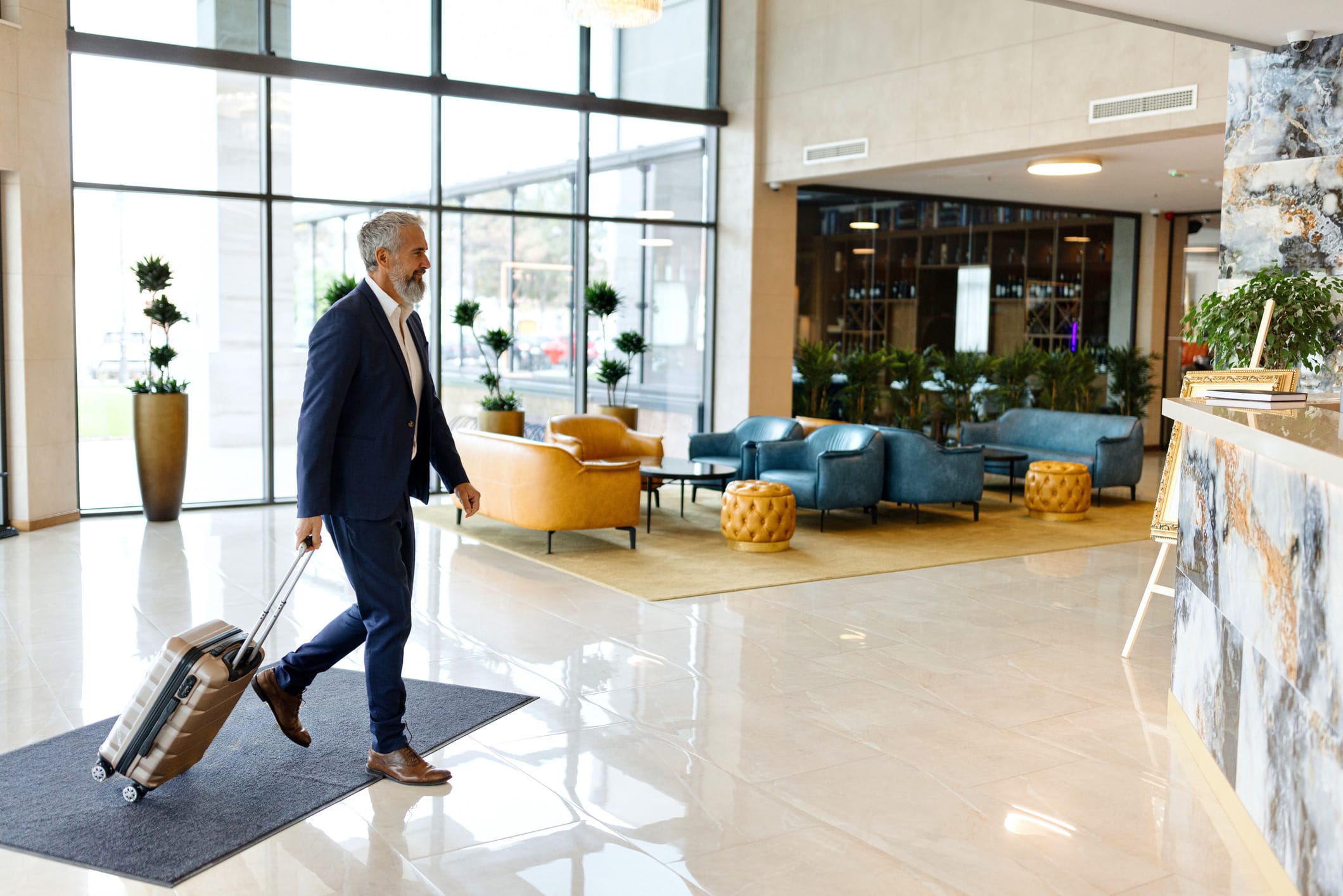 Man in a suit with luggage walks through a hotel lobby, reflecting hospitality revenue optimization.