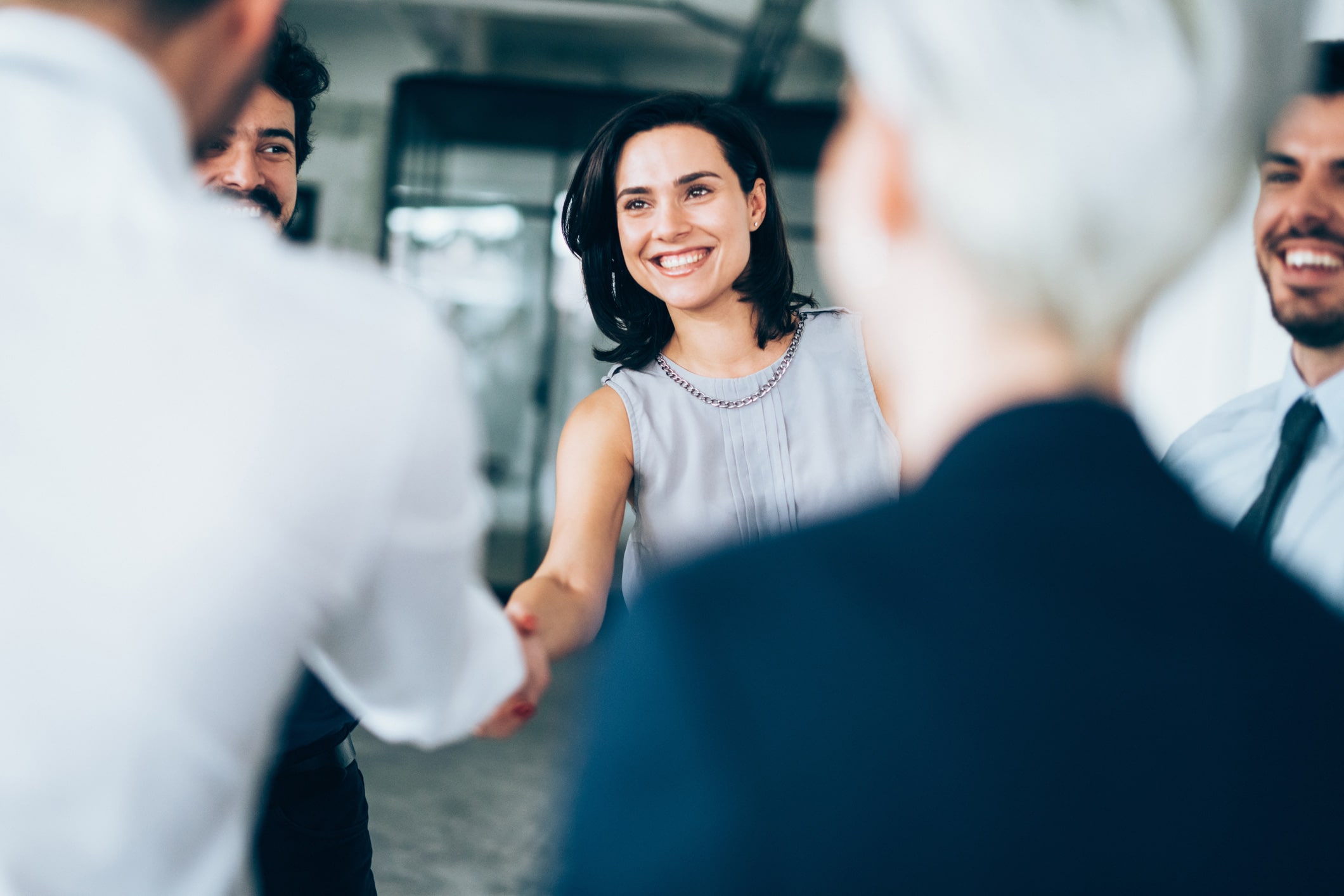 Smiling woman shaking hands with a colleague during a leadership transition consulting meeting.