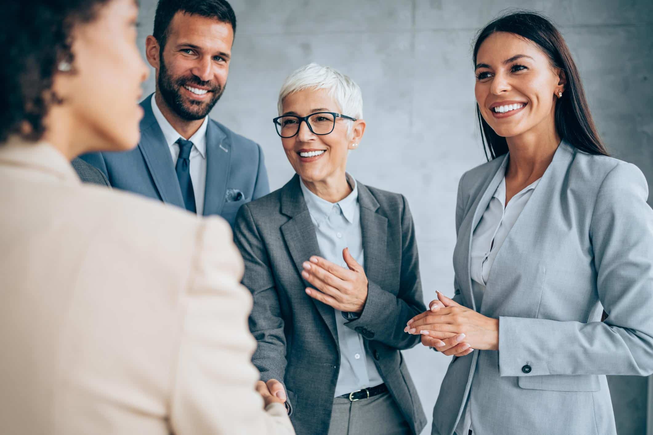 Four business professionals smiling in a hospitality talent acquisition consulting office.