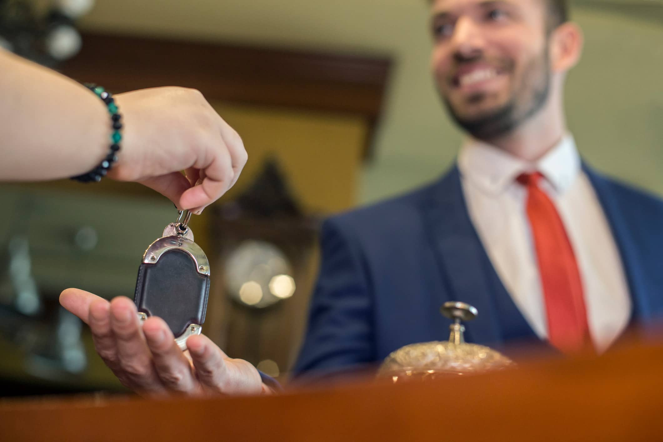 A person hands a room key to hotel receptionist, showcasing personalized hospitality merchandising.