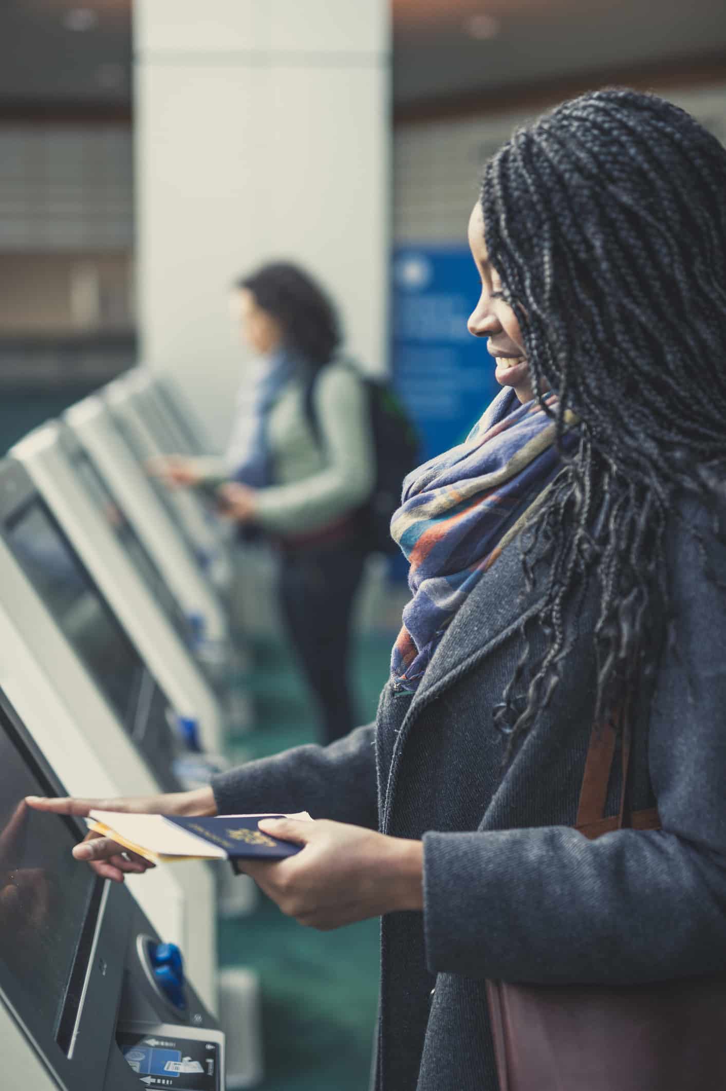 Woman uses an airport kiosk, embracing paperless airline crew & operations workflow solutions.