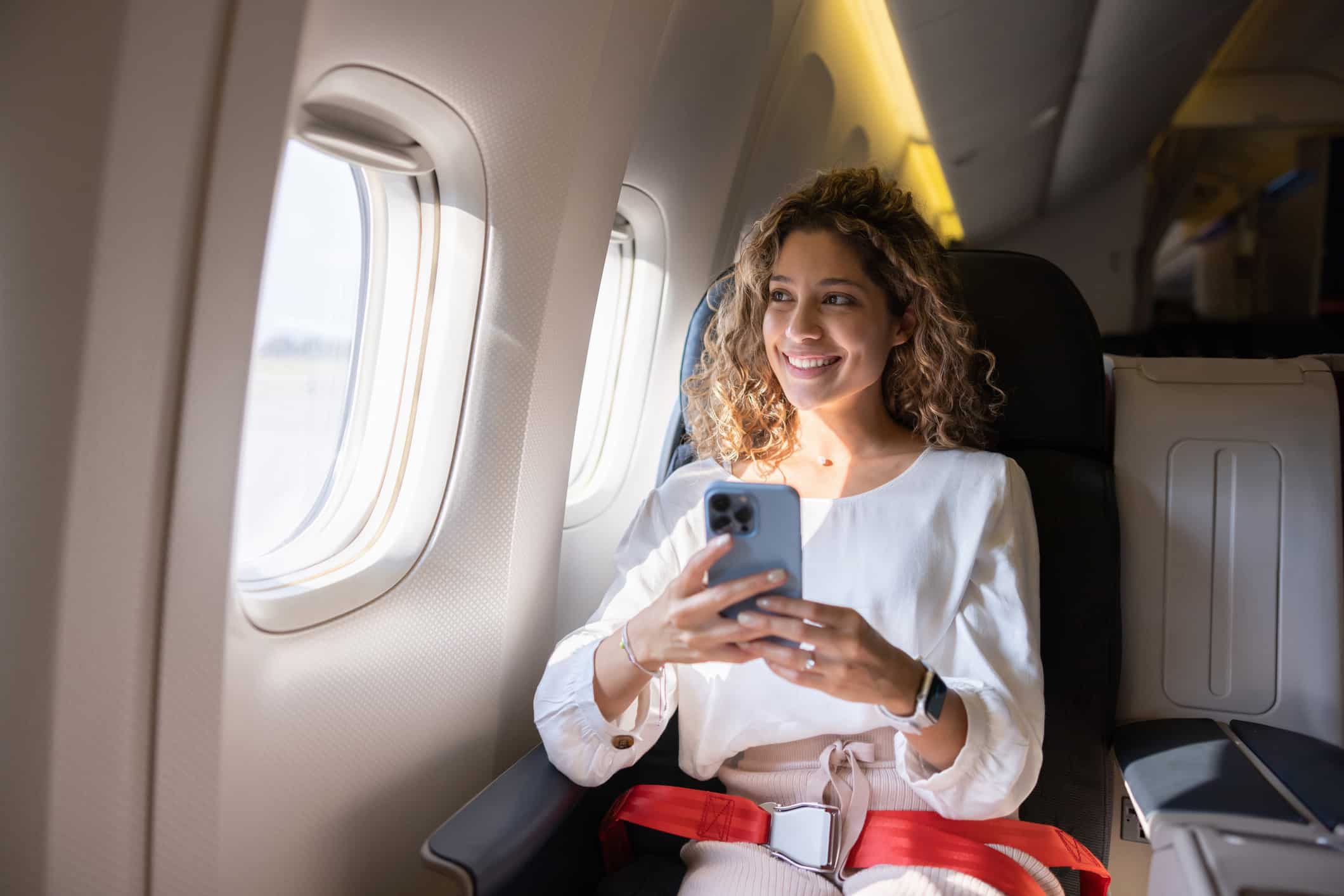 Woman smiling with phone, showcasing airline passenger experience innovation onboard.