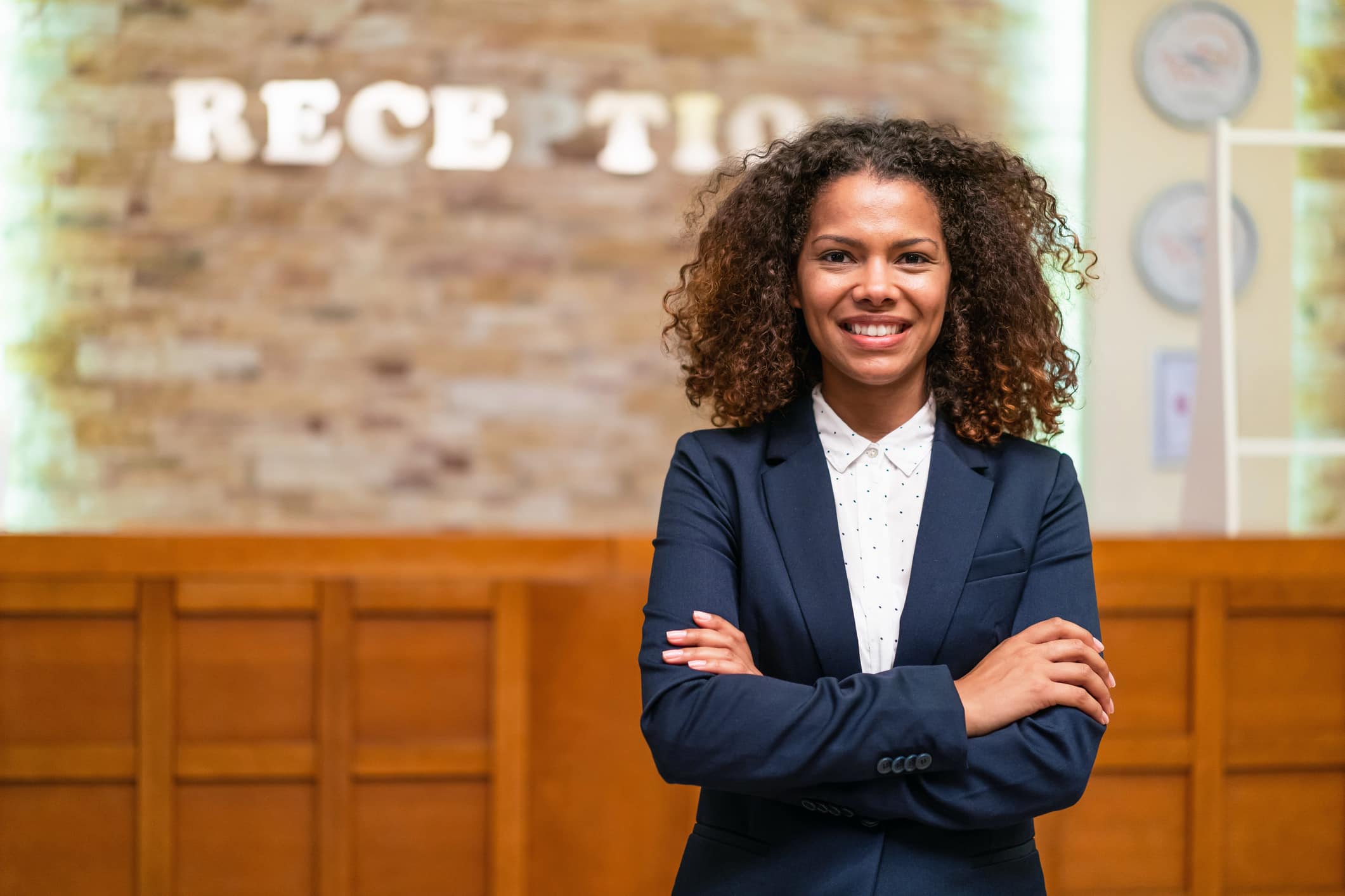 Smiling woman in a suit stands with arms crossed, embodying shared economy business model strategy.