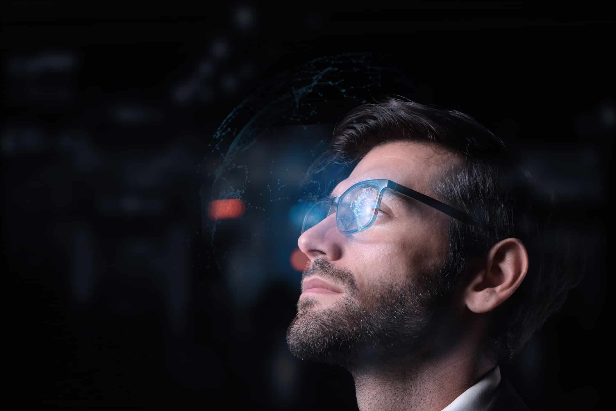 A man with glasses studies glowing digital data, reflecting on Voice of the Customer (VoC) Analytics