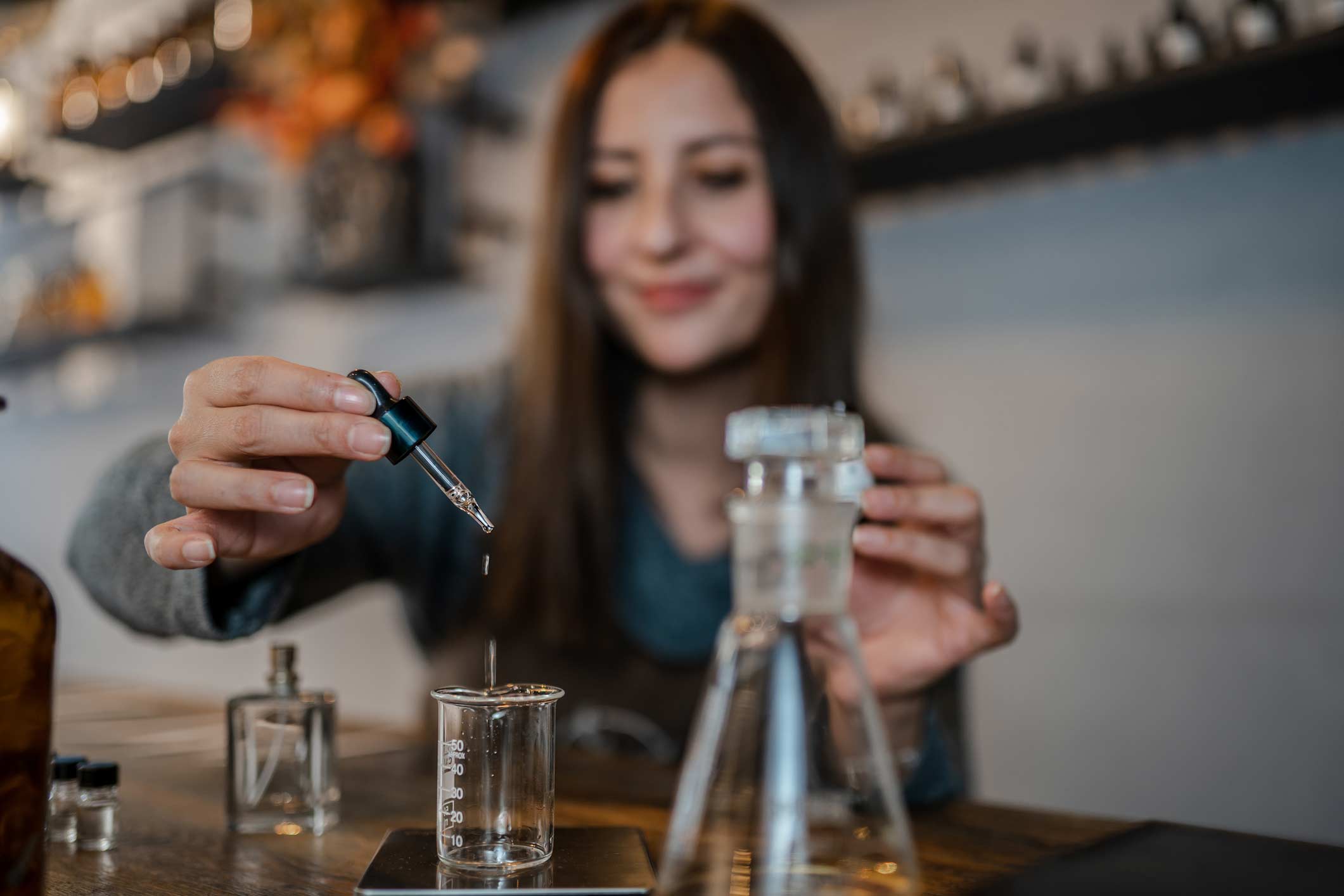Woman uses a dropper to add liquid to beaker symbolizing Hospitality AI, Data & Cognitive Science