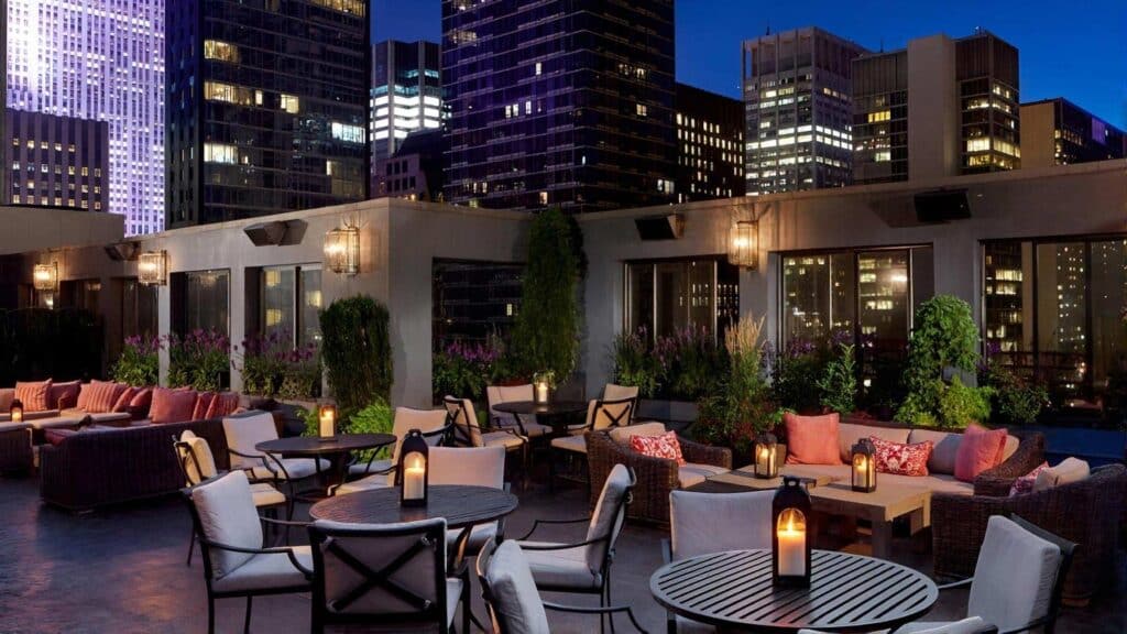 Rooftop lounge with cozy seating, candlelit tables, and a hospitality consulting firm touch.
