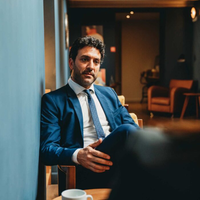 Man in a blue suit sits thoughtfully in an office, reflecting on hospitality consulting.