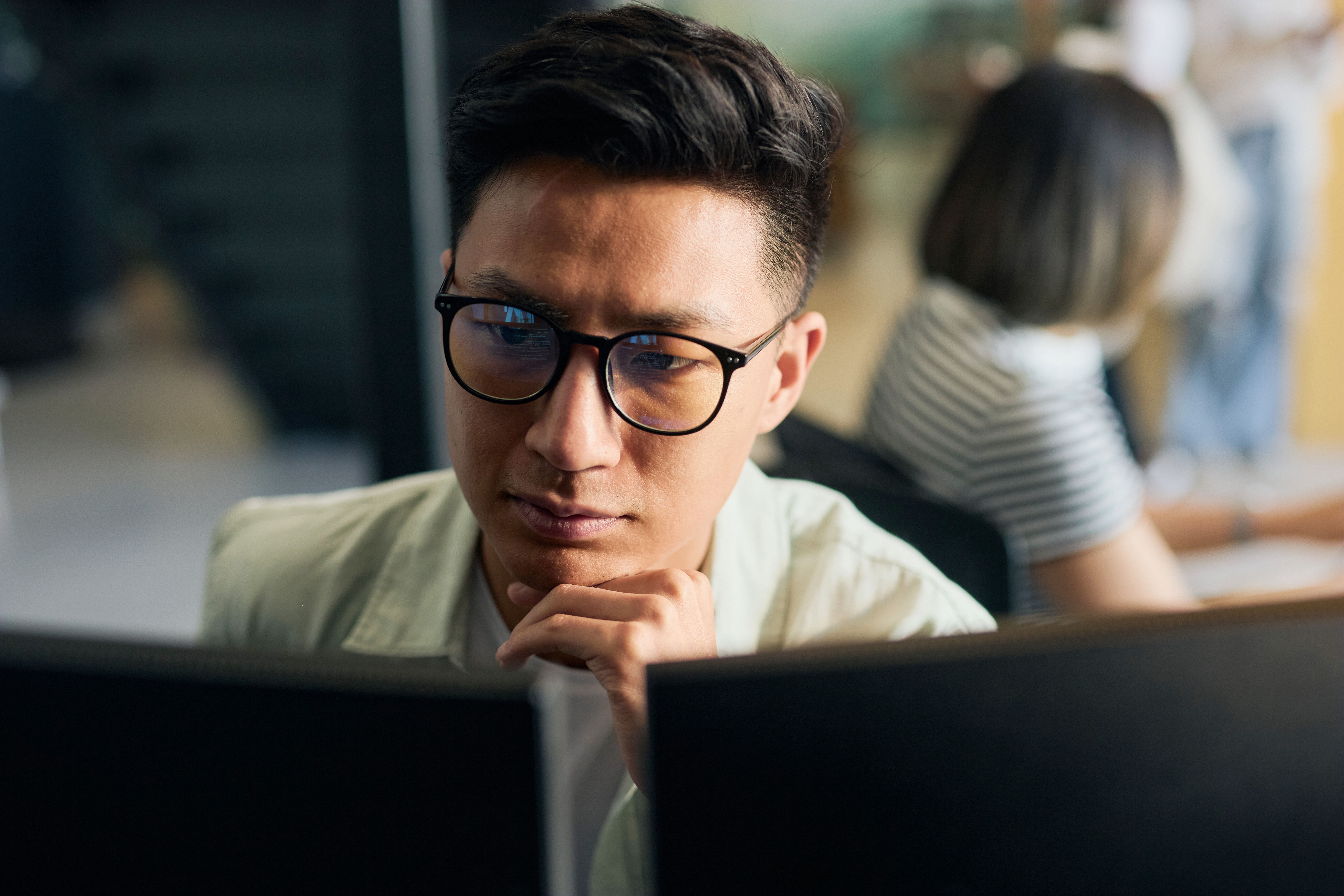 Man with glasses concentrating while working on artificial intelligence consulting in an office.