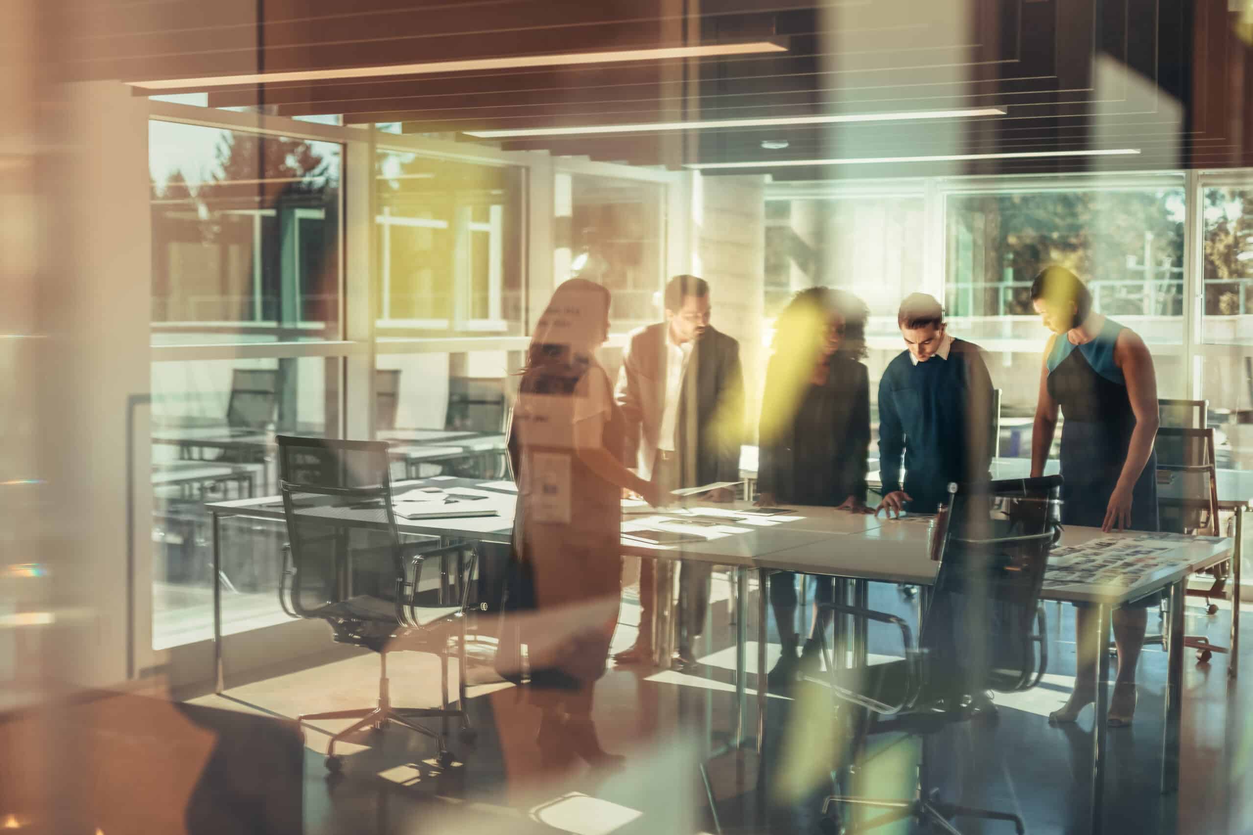 Five people discuss around a table in a bright, modern office, focused on AI governance consulting.