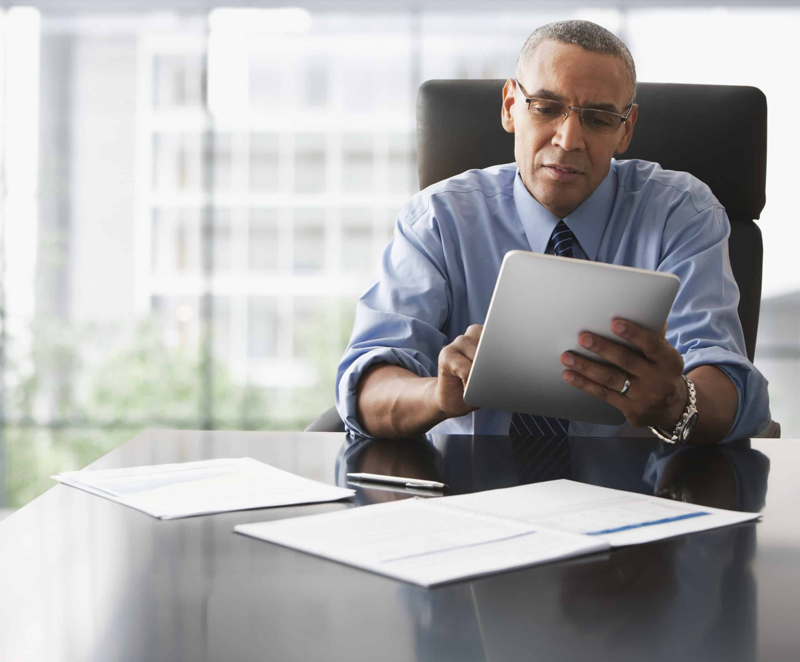 Man in office using a tablet, exploring business model transformation consulting strategies.