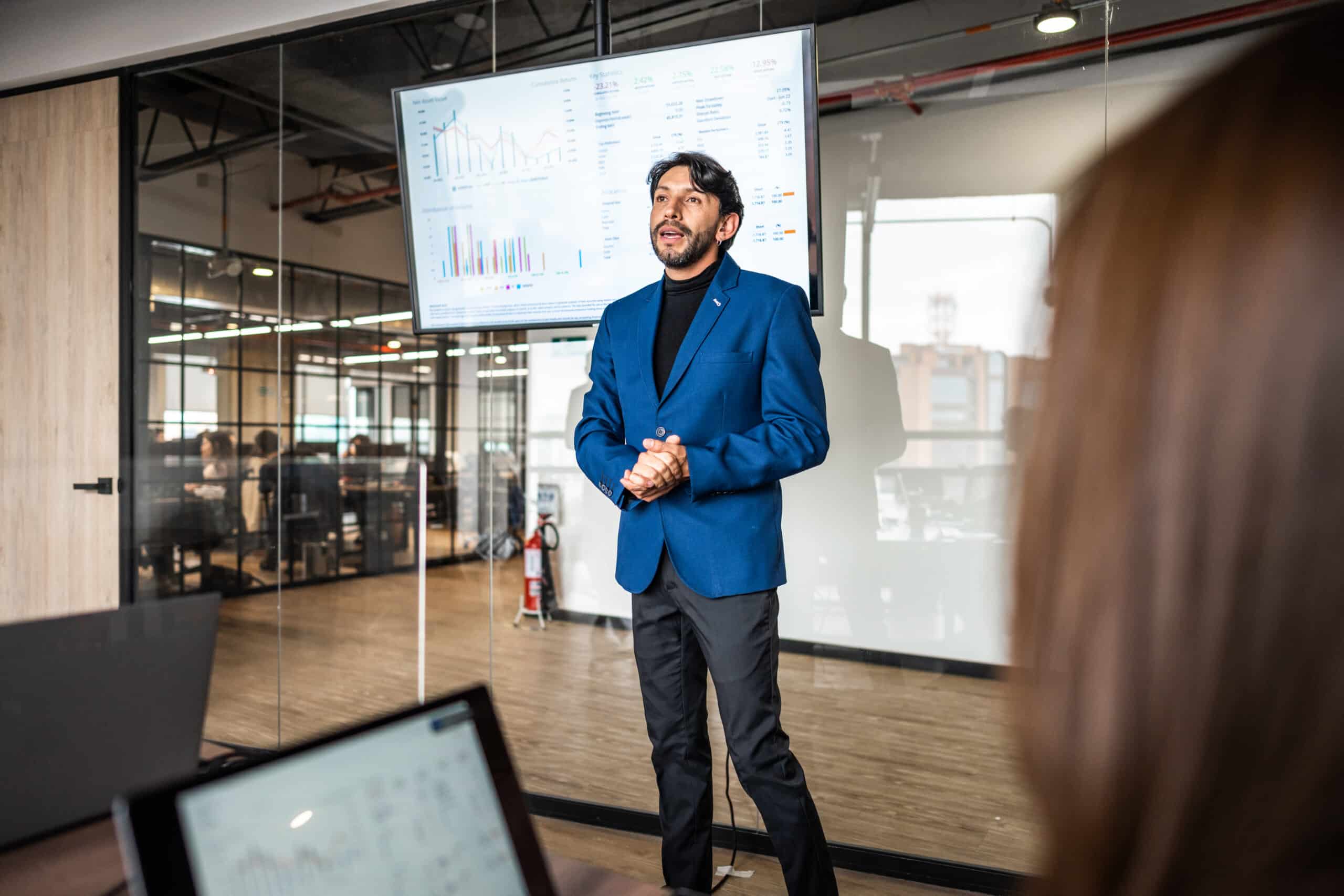 Man in blue blazer presenting business model transformation charts in a modern office.