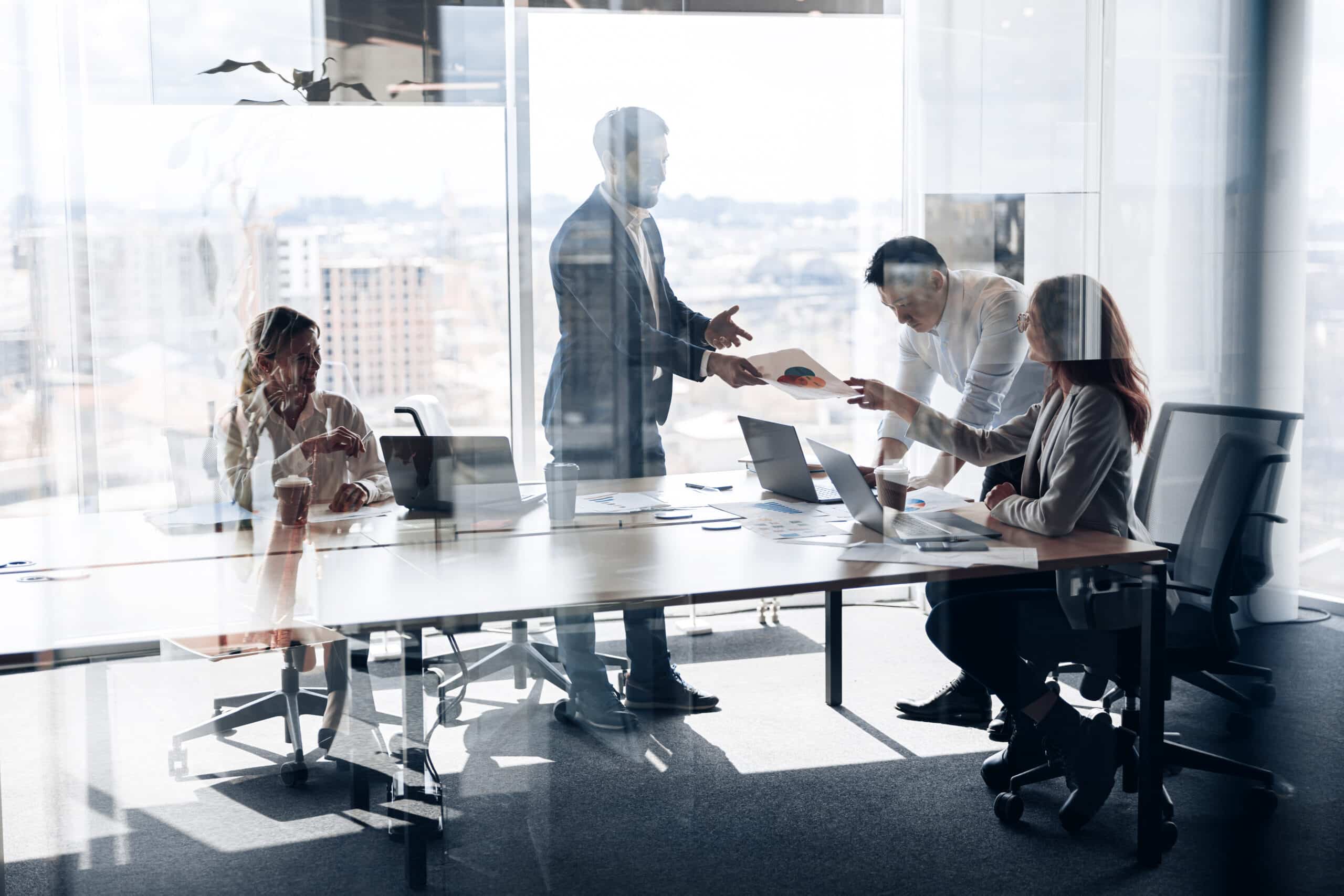 Four colleagues discuss strategy in a modern office, focusing on commercial real estate asset management.