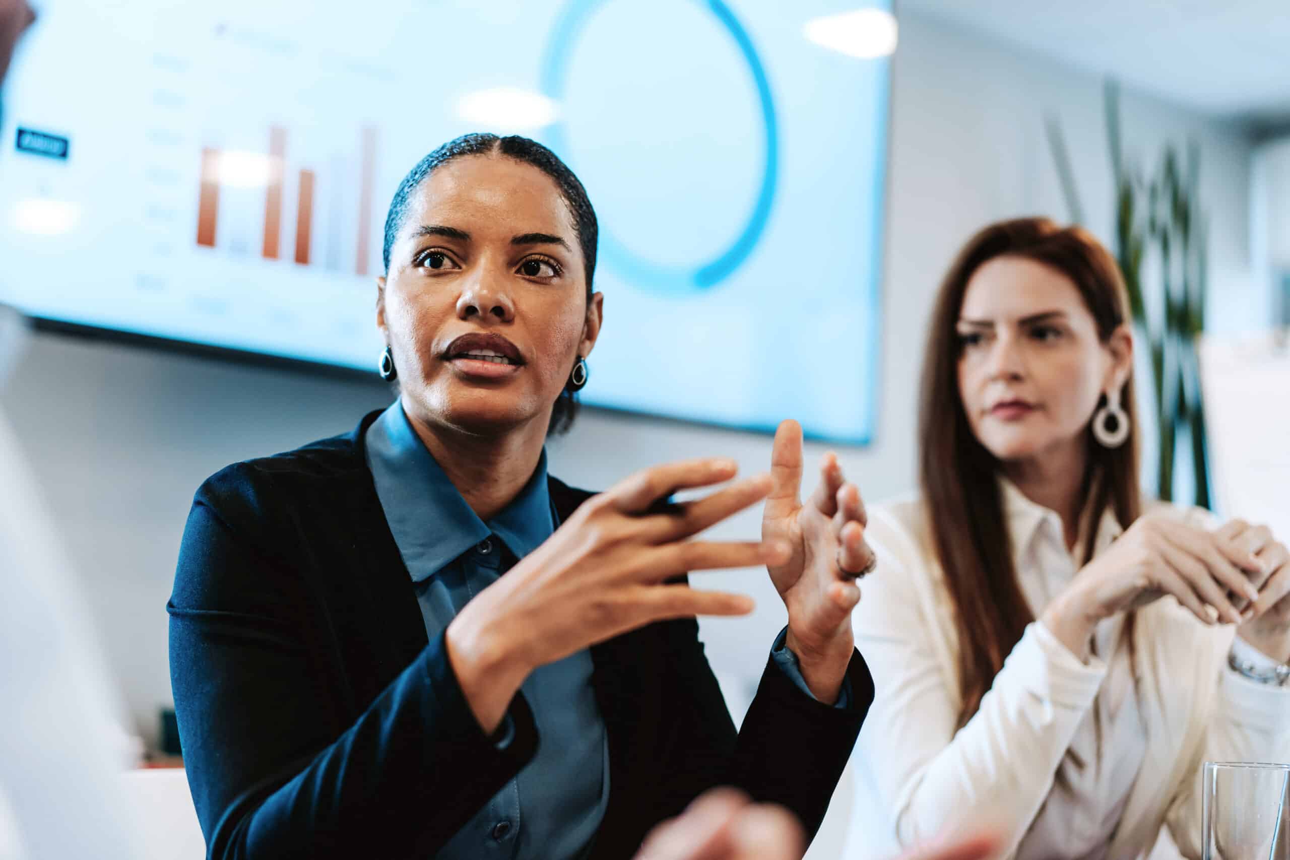 Two women in a meeting on commercial real estate due diligence, chart displayed behind them.