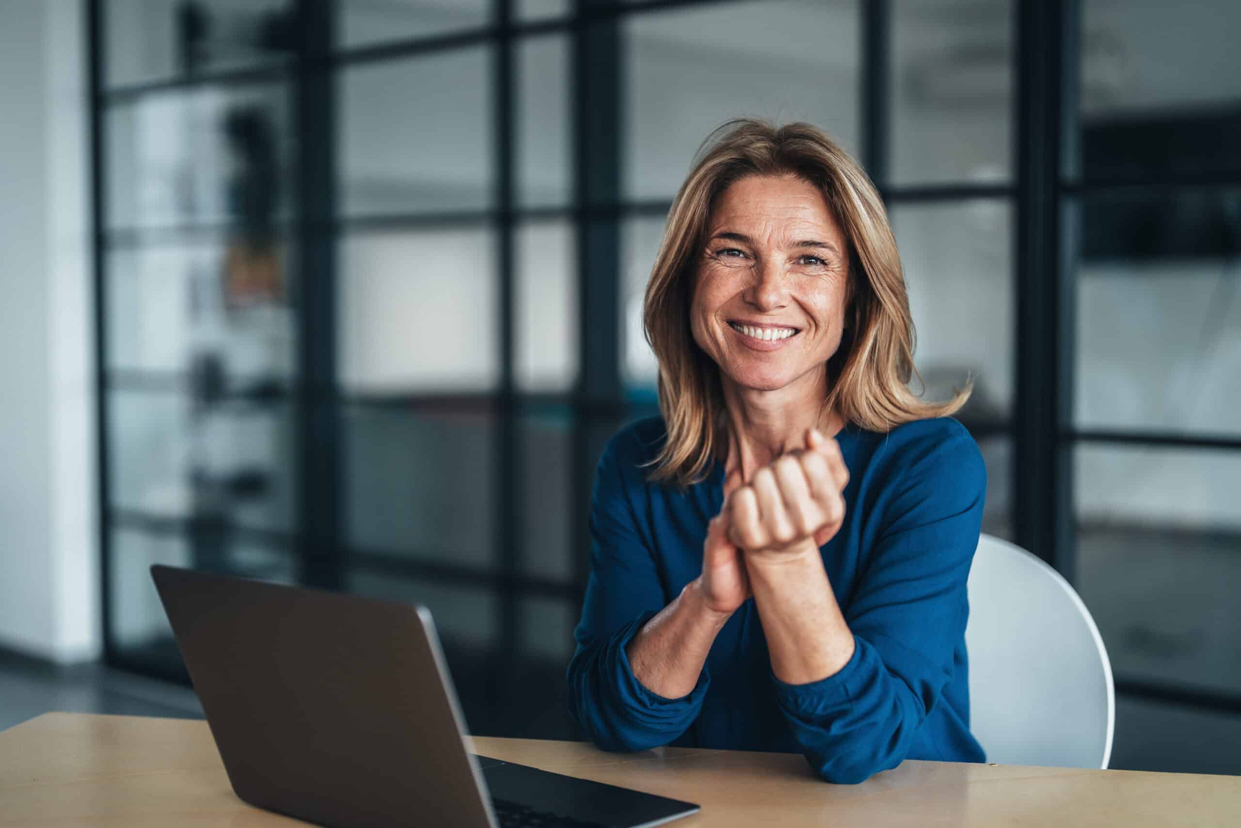 Smiling woman in blue shirt works on commercial real estate facilities management consulting.