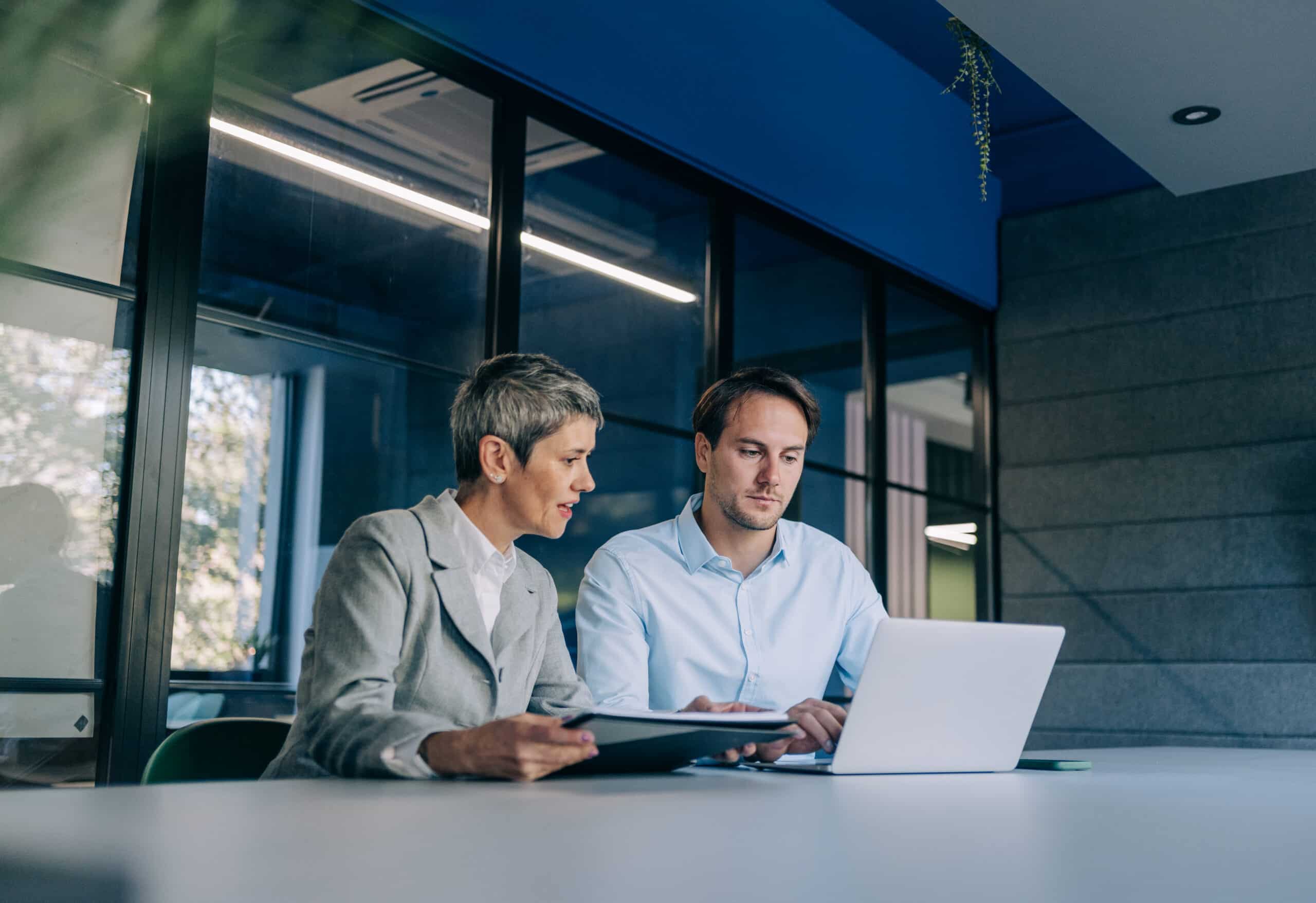 Two colleagues at a desk collaborating on commercial real estate facilities management.
