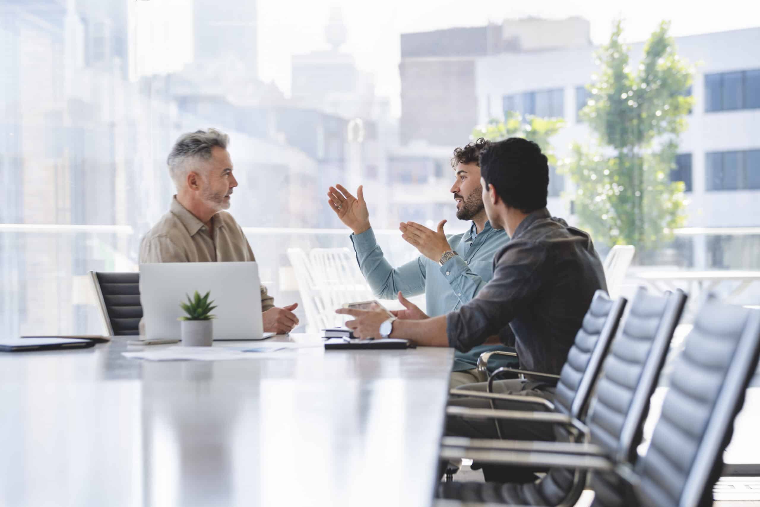 Three men discuss commercial real estate operations in a bright, modern office.