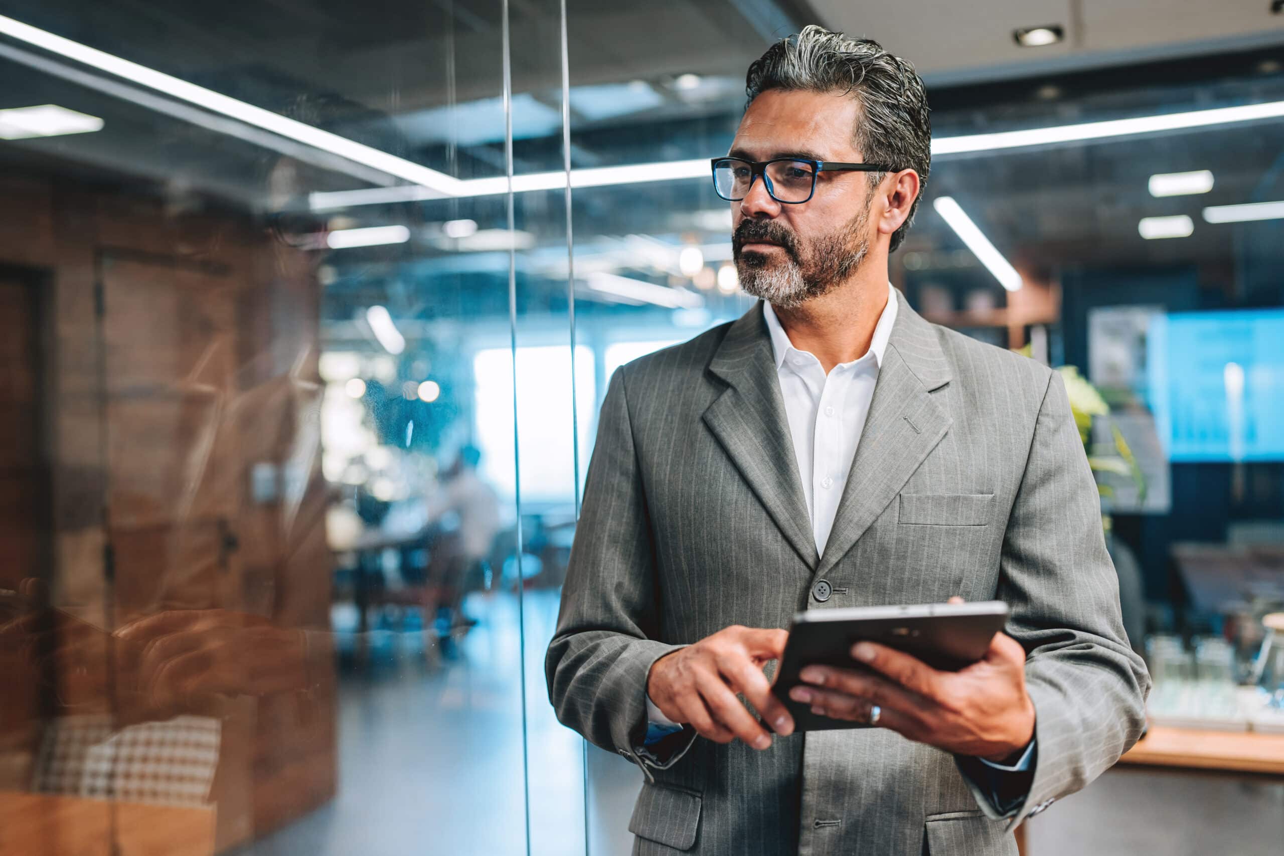 Man in a gray suit holding a tablet, showcasing commercial real estate operations consulting.