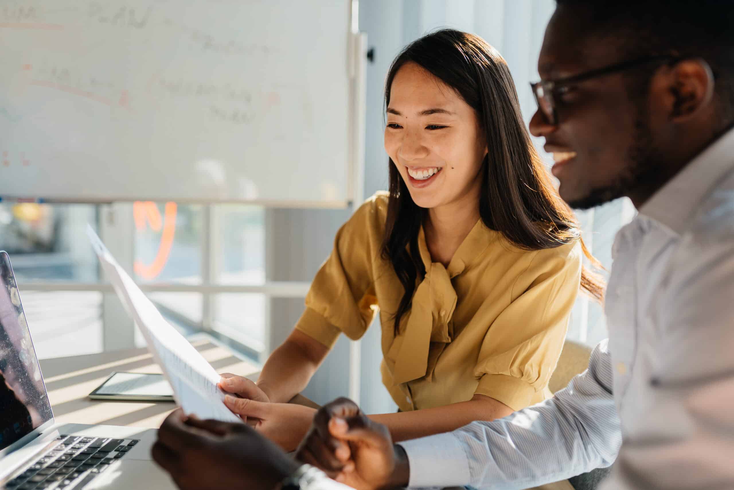 Two colleagues smiling and collaborating on commercial real estate tech strategy at a desk.