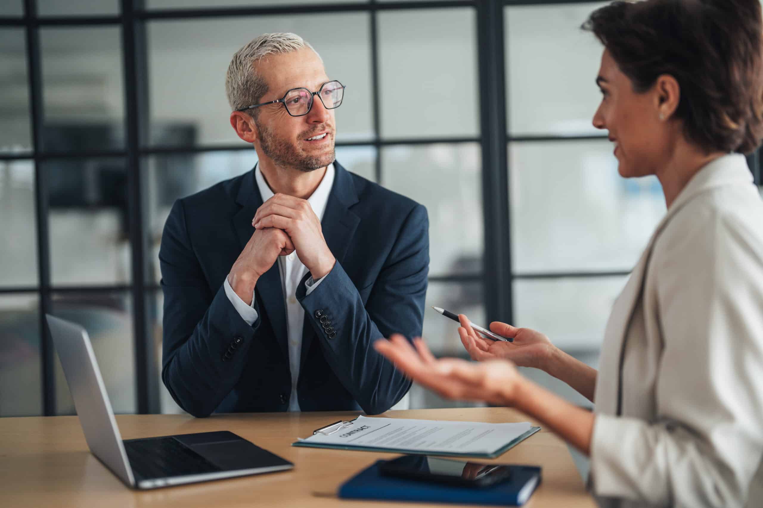 Two professionals discuss commercial real estate workplace strategy at a desk with a laptop.