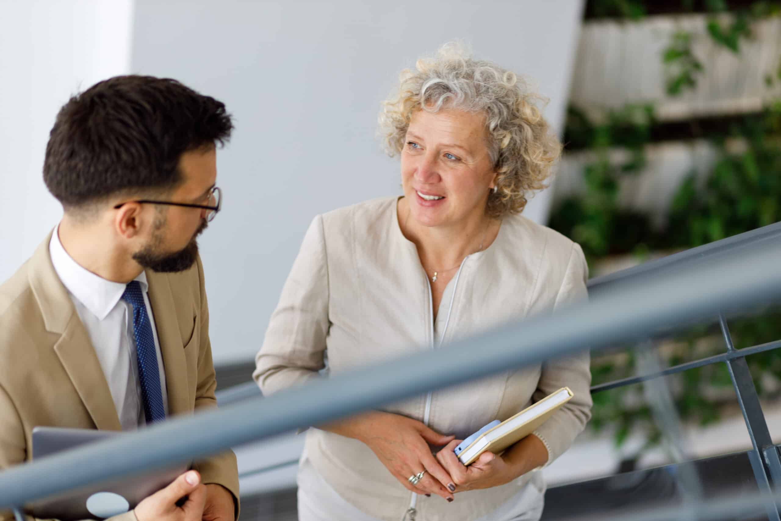 Two people in business attire discuss capital allocation strategy while walking up stairs.