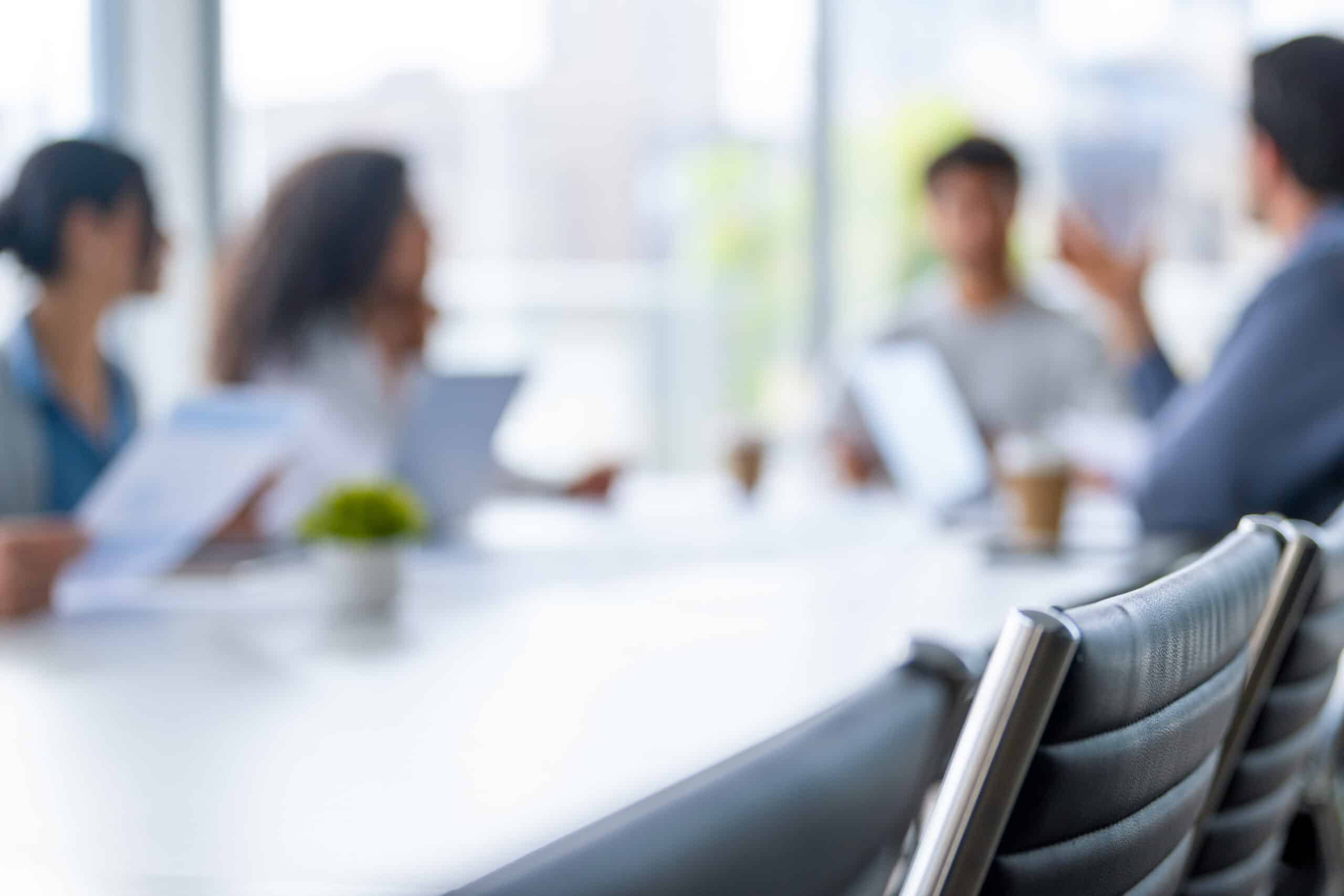 Four people in a blurred office meeting, discussing cloud migration around a conference table.