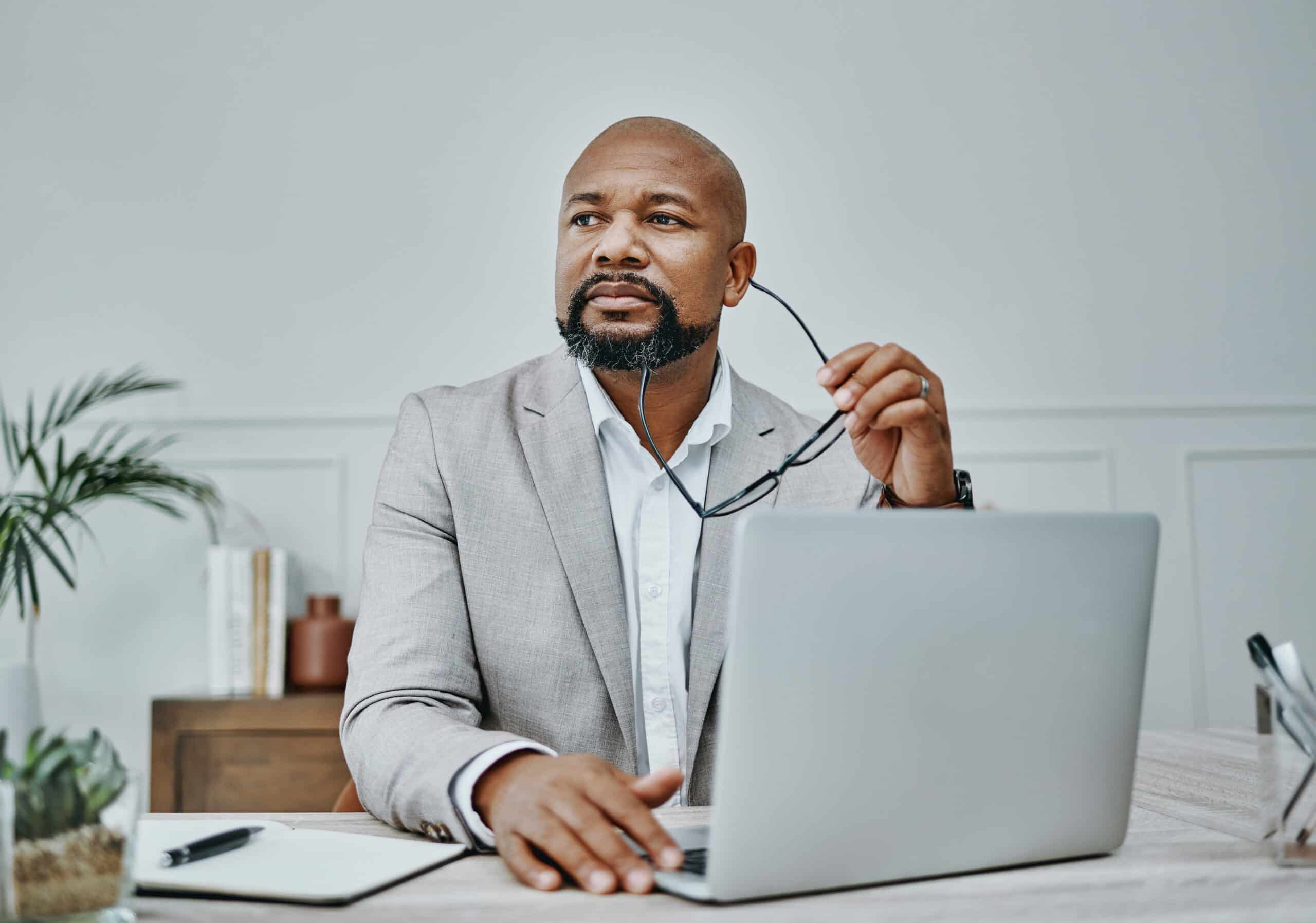 Man in a light suit sits at a desk, pondering data quality services on his laptop.