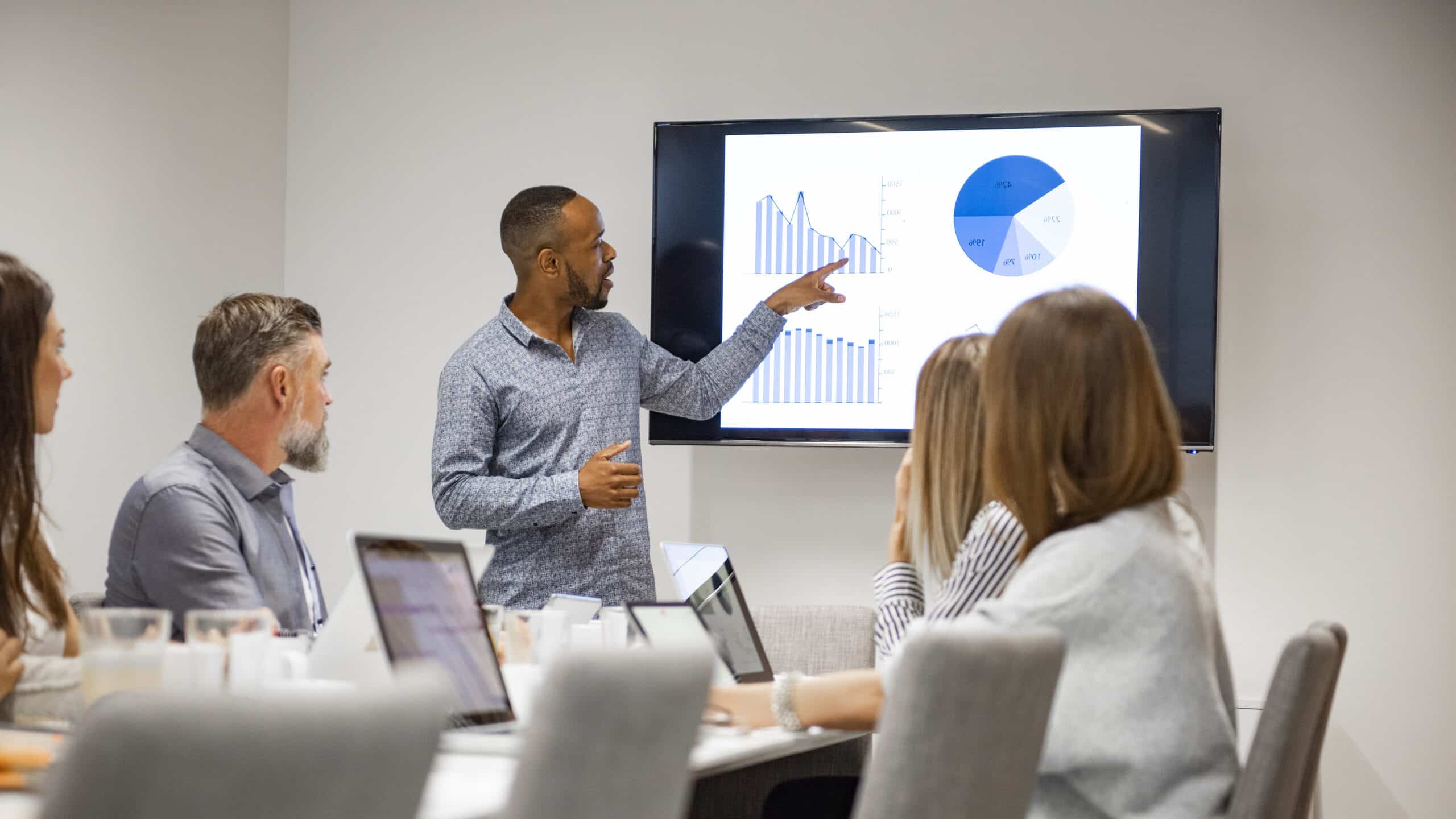 Man presenting digital twins data to colleagues in a conference room meeting.
