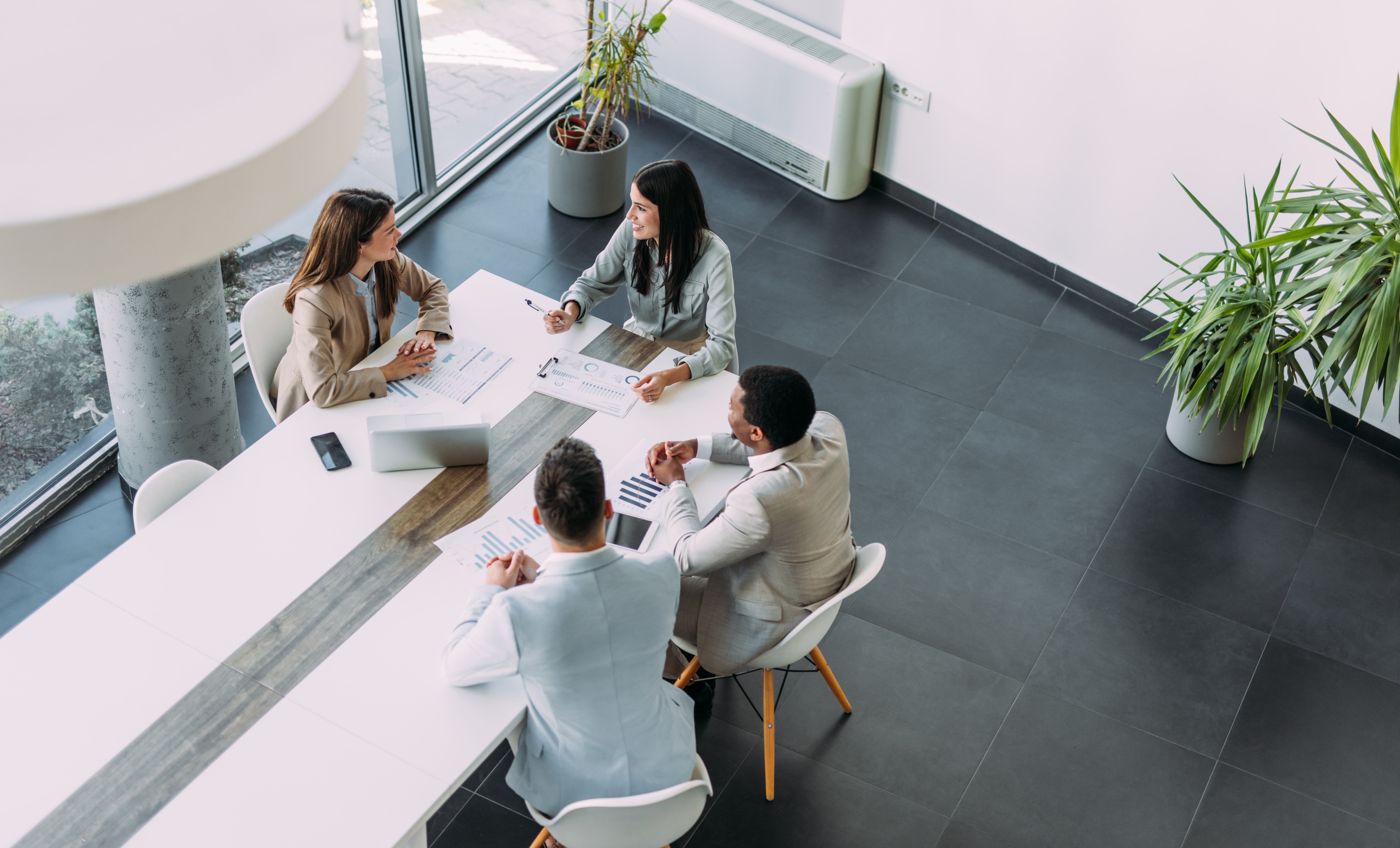 Four people in business attire discuss eminent domain consulting in a modern office setting.
