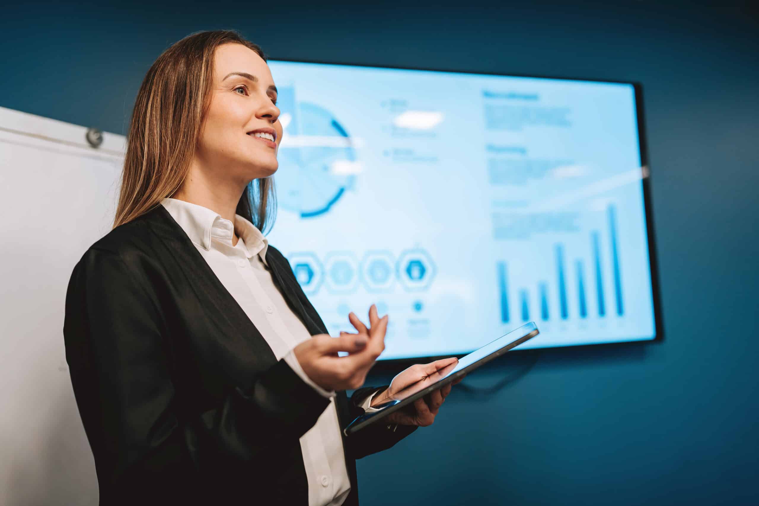 Woman presenting with a tablet, showcasing enterprise application integration on screen.