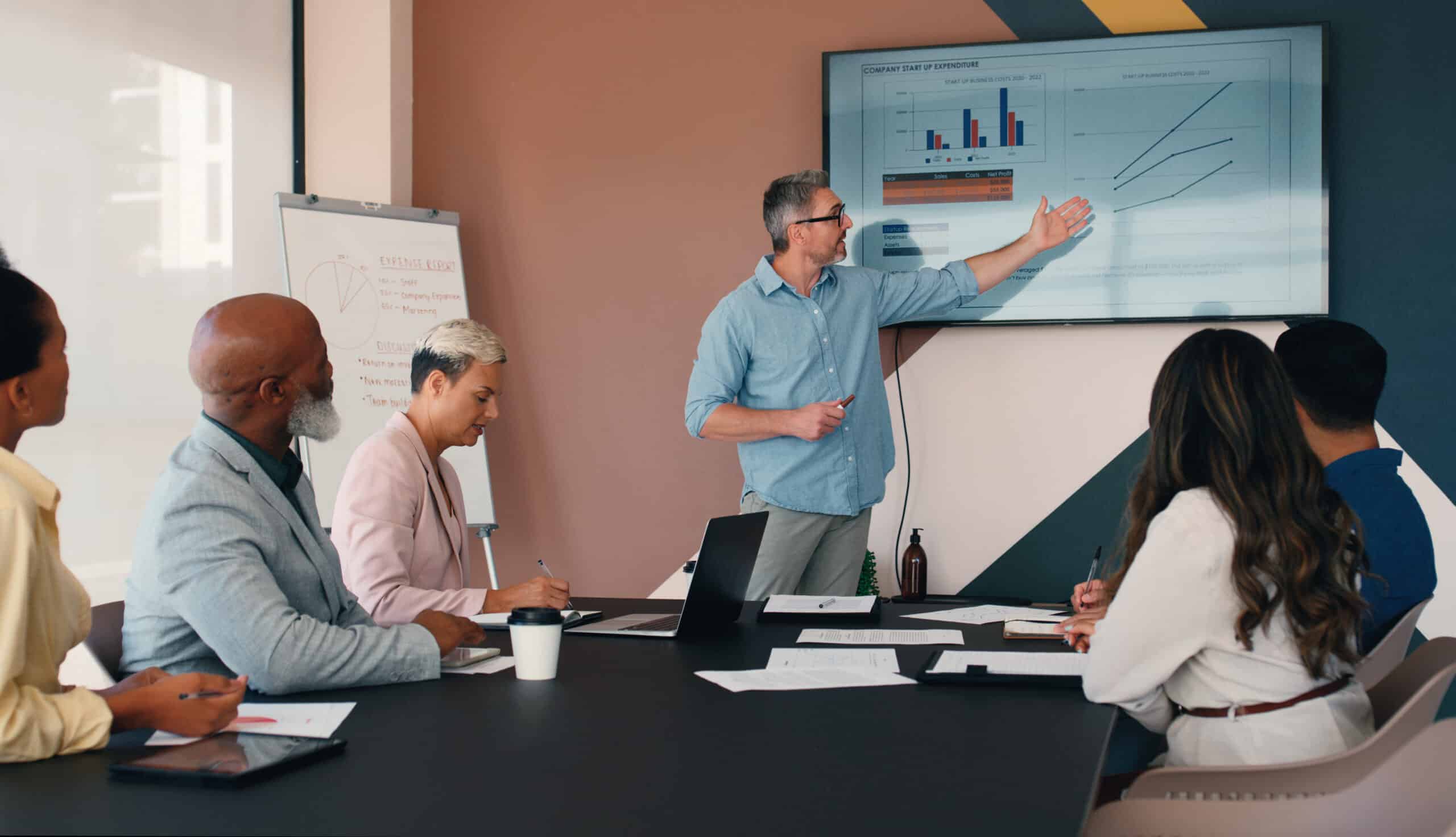 Man presenting graphs to colleagues, discussing enterprise application integration strategies.