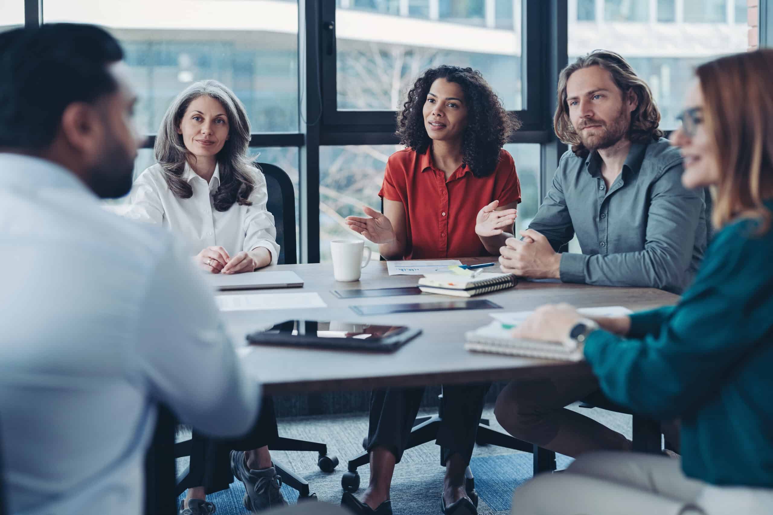 Five people discuss enterprise application integration in a modern office setting.