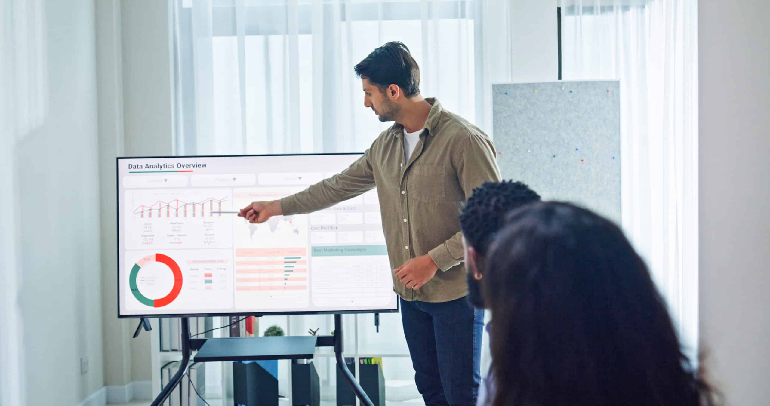 Man presenting data charts on enterprise systems transformation to colleagues in a bright office.