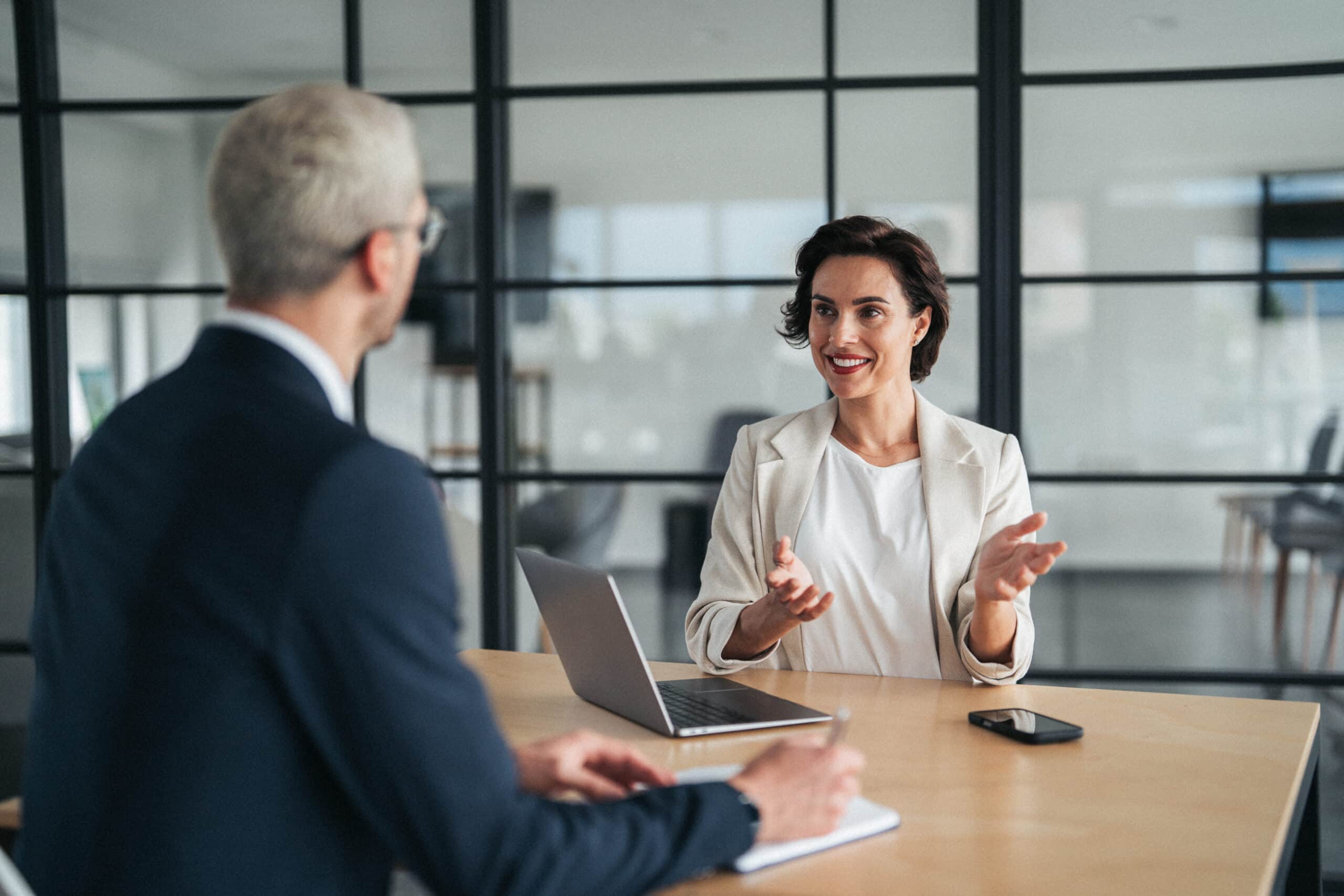 Two people discuss expert witness services consulting at a desk in a modern office.