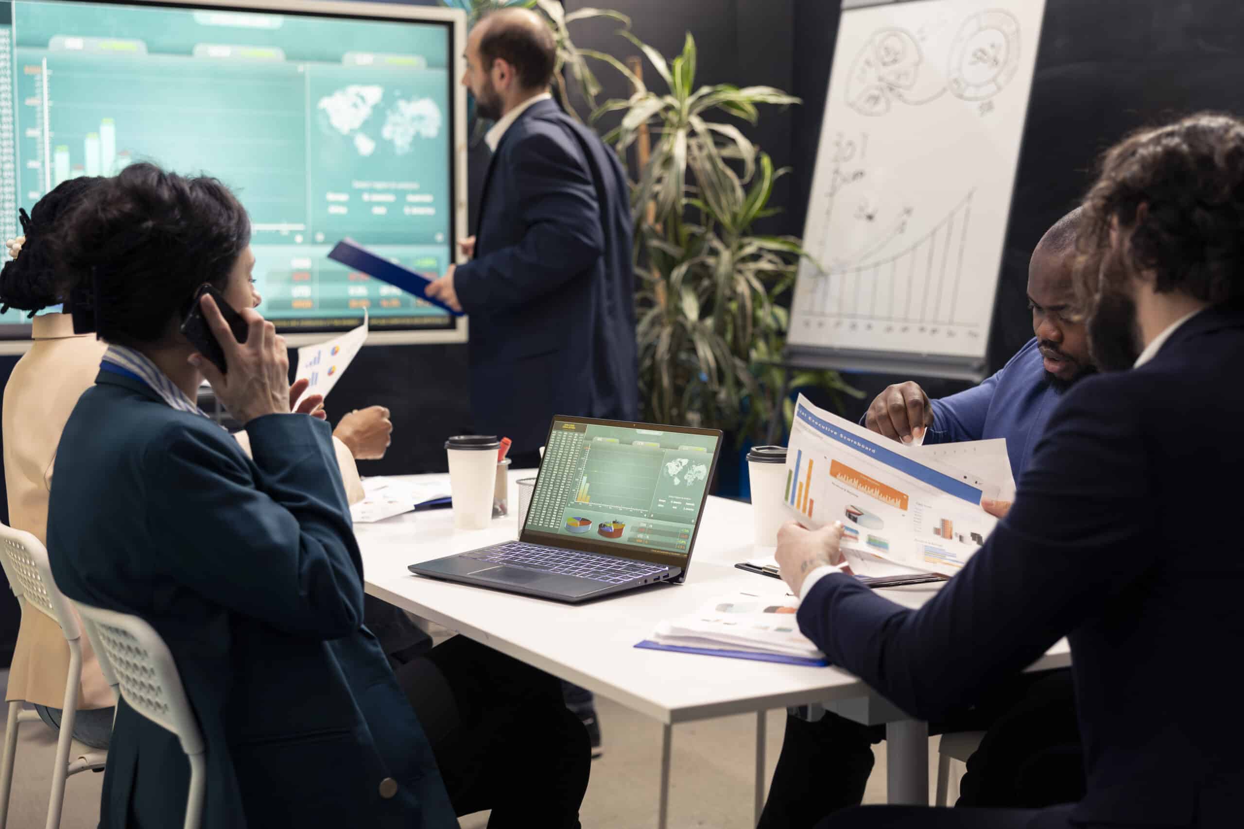 Business team analyzing charts with geospatial analytics consultants in a conference room.