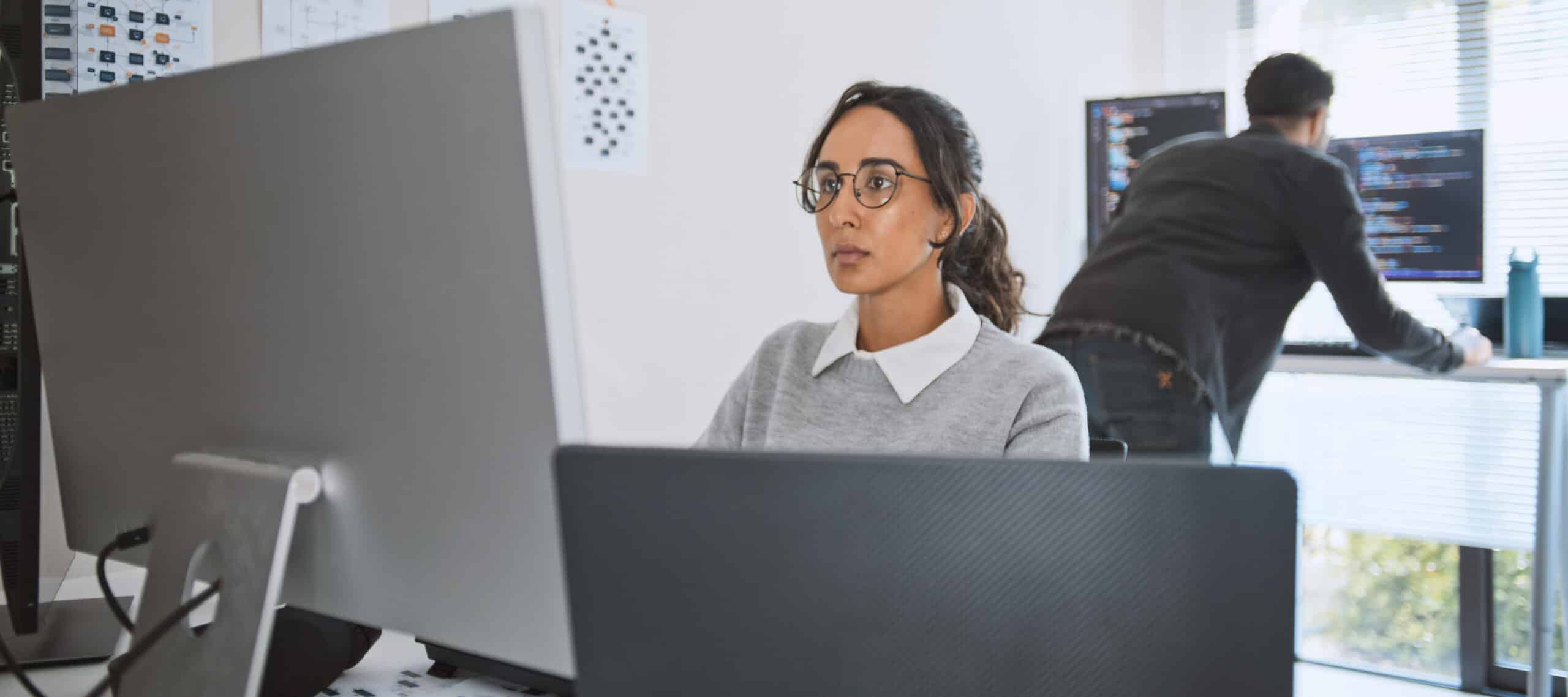 Woman working at a computer in an office, specializing in geospatial analytics consulting.