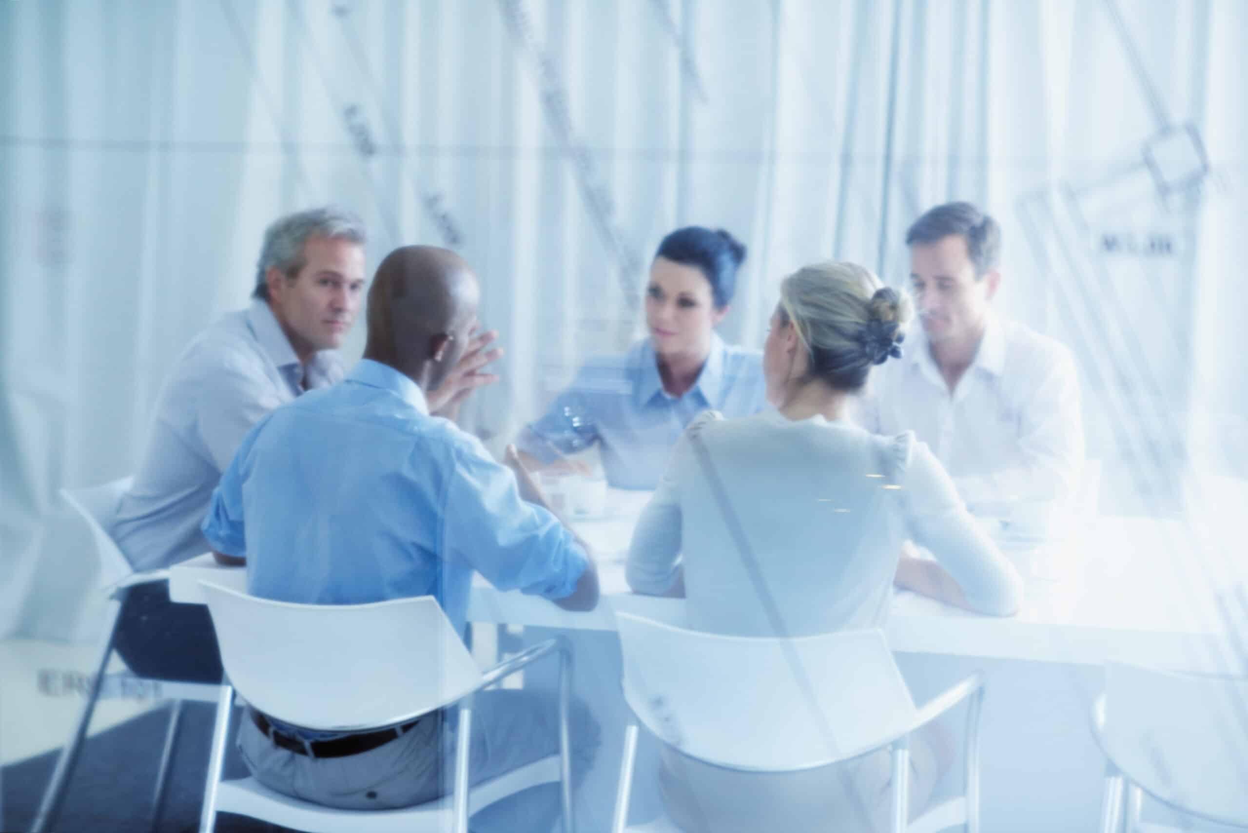 Five people sit around a table in an office, discussing IT modernization consulting.