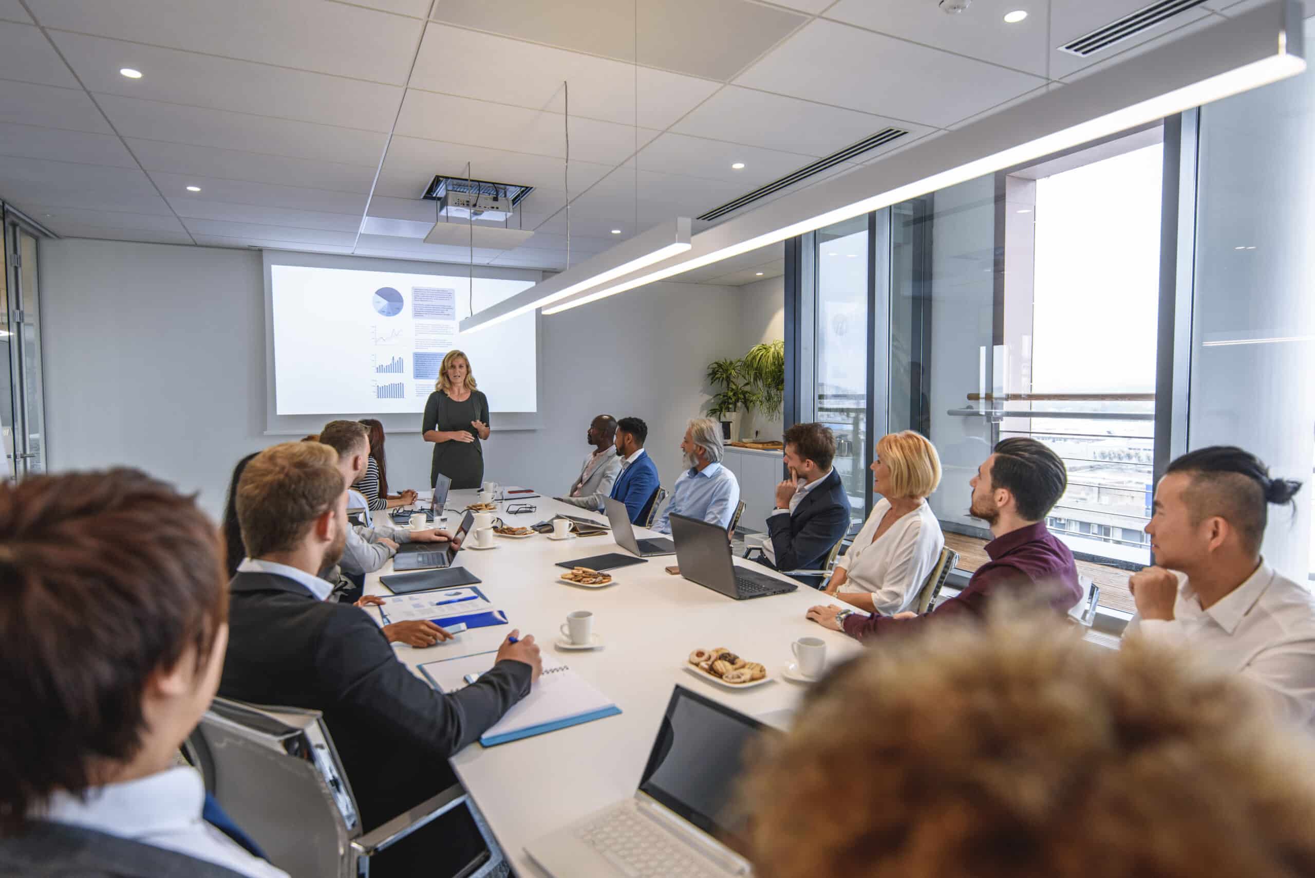 A woman presents it modernization strategies to colleagues in a modern conference room.