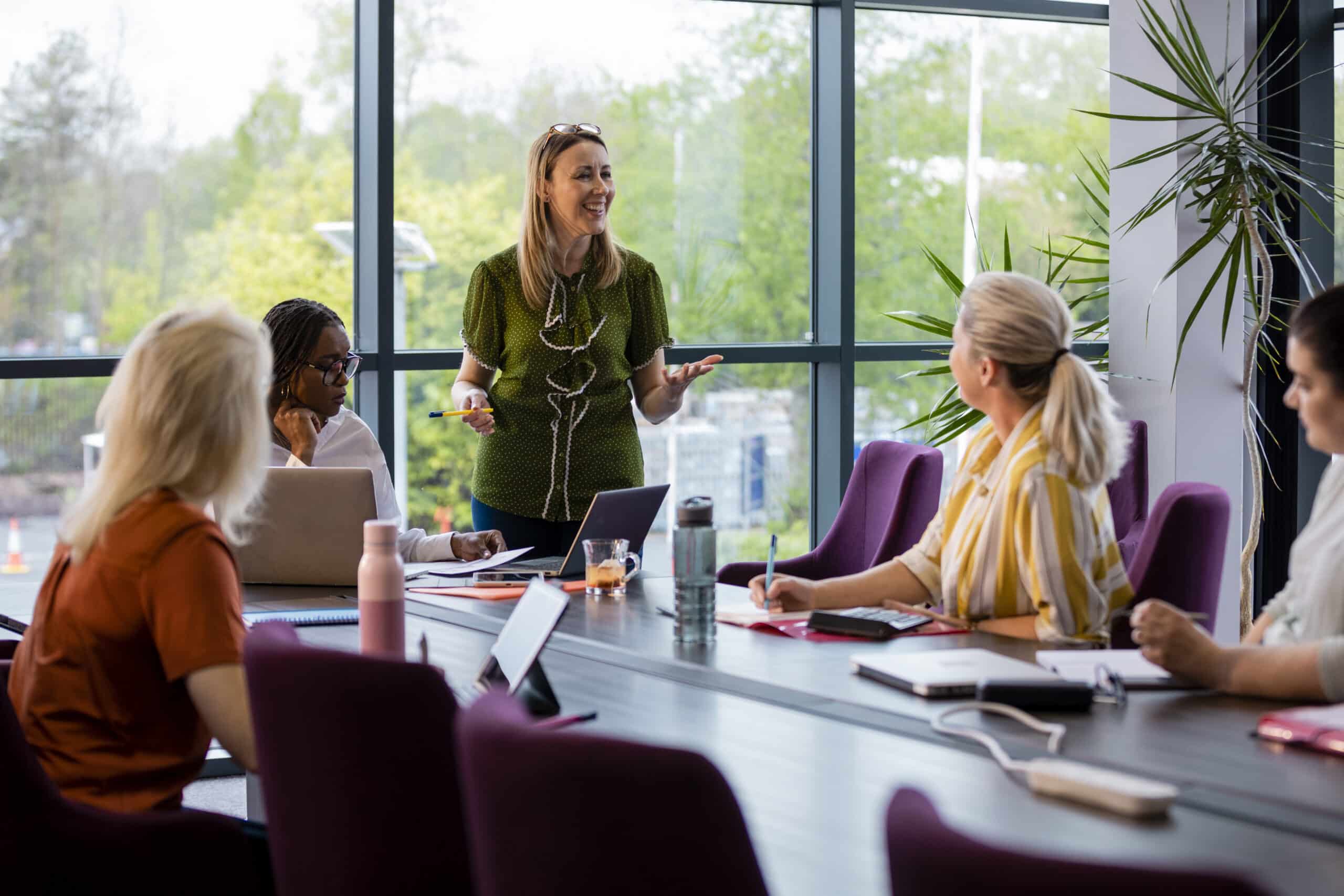 Four women sit at a conference table as a land use planning consultant presents to them.