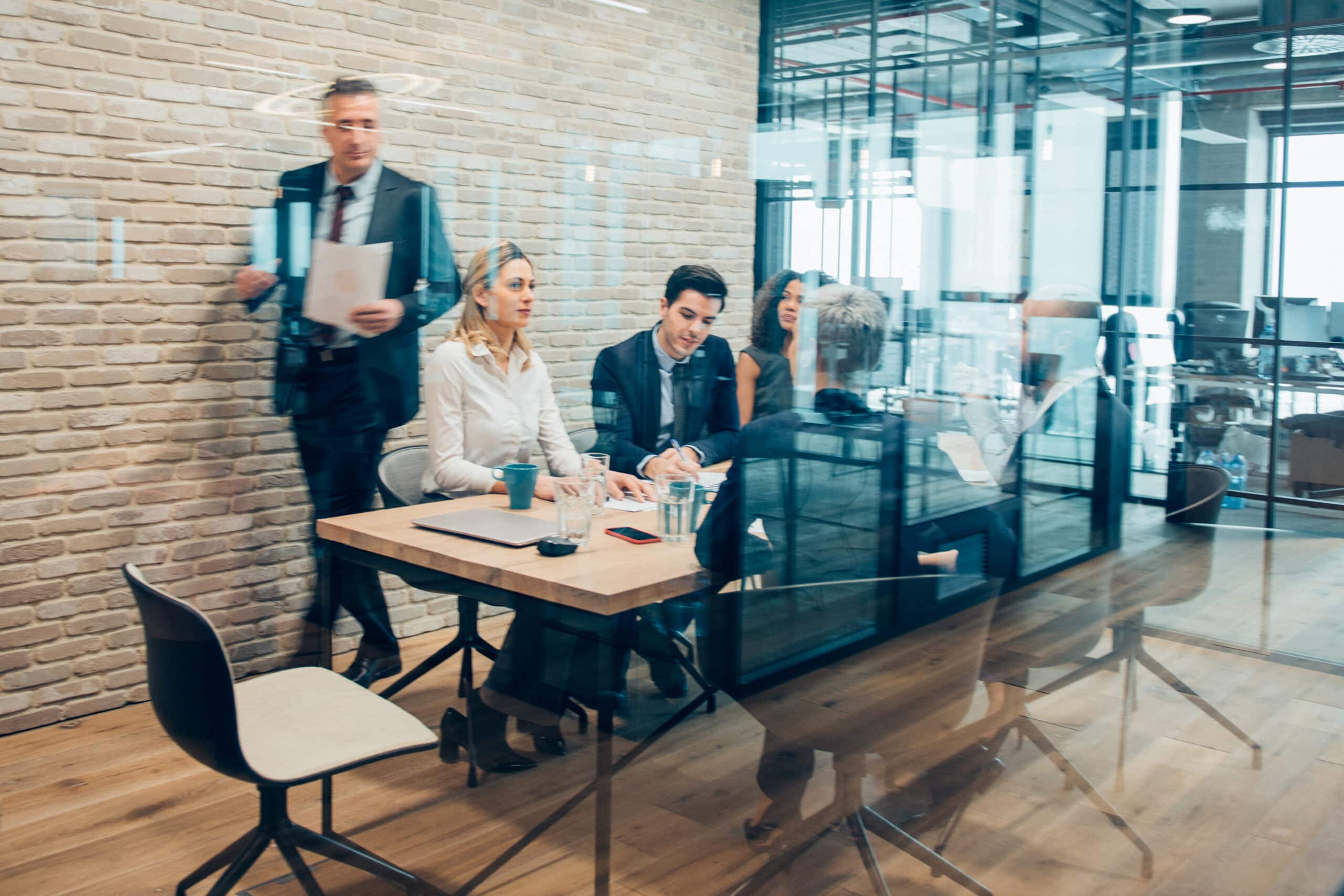 Group of people having a meeting with land use planning consultants in a modern glass-walled room.