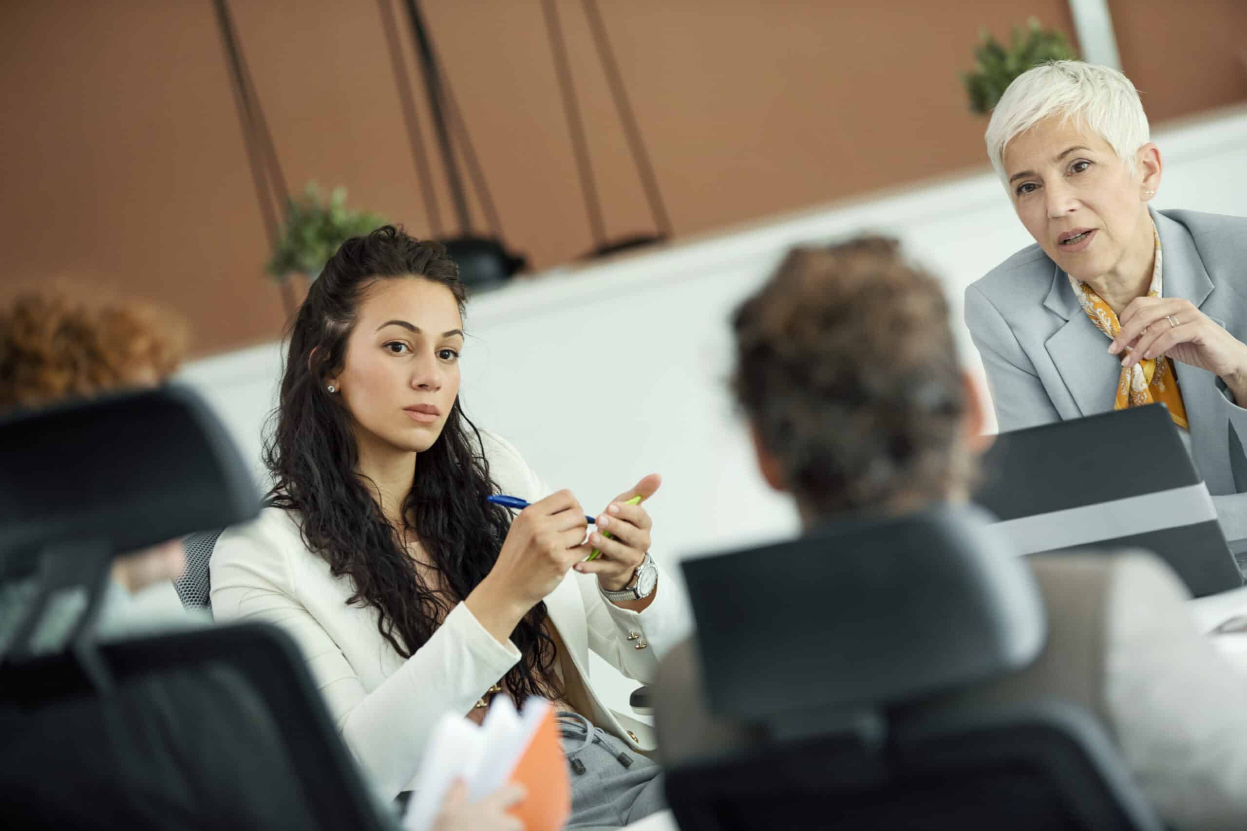 Four people discuss land use planning consulting at a business meeting around a table.