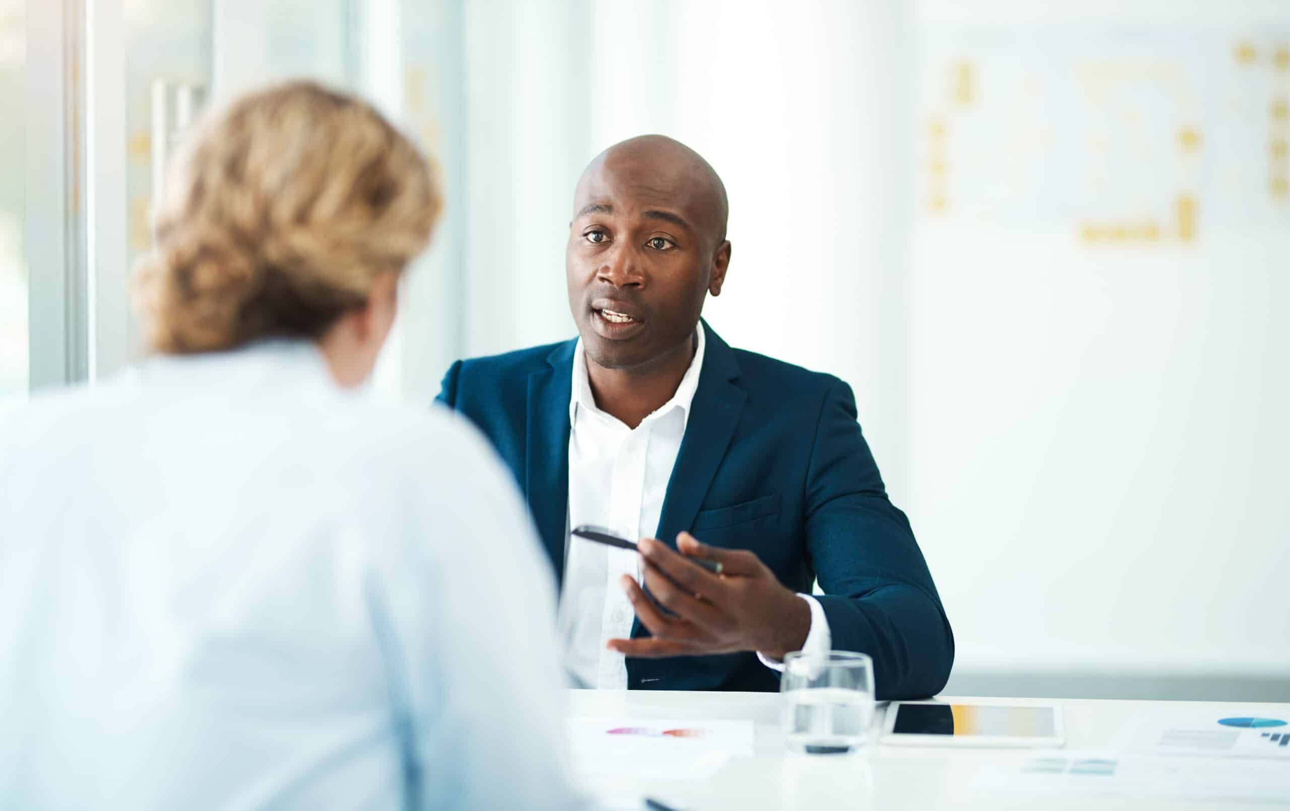 Two people in a business meeting, discussing predictive maintenance consulting at a desk.